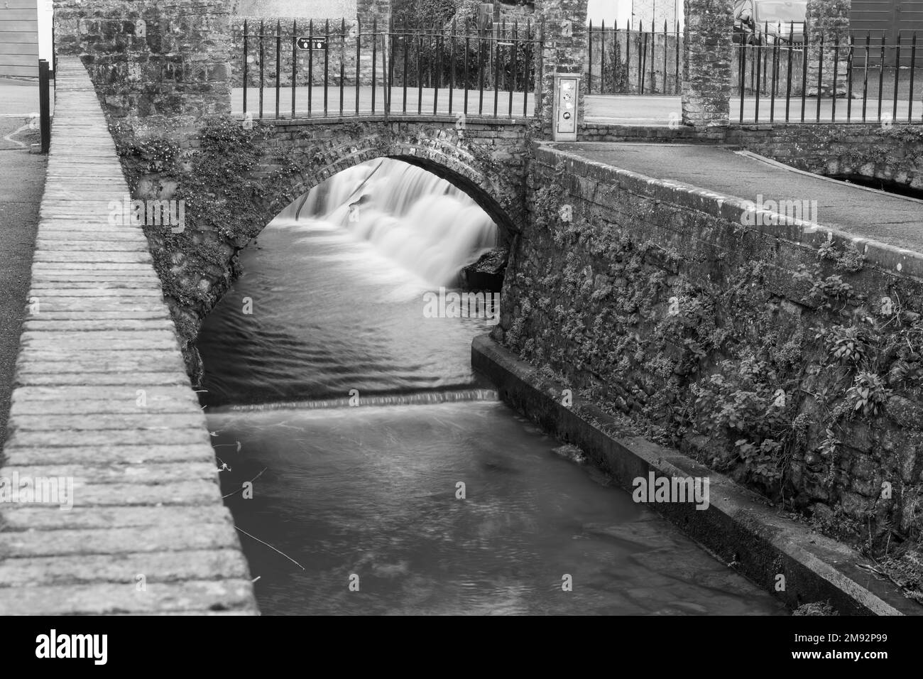 Longue exposition d'un écoulement d'eau sous un pont sur la rivière Lim Walkway à Lyme Regis dans Dorset. Banque D'Images
