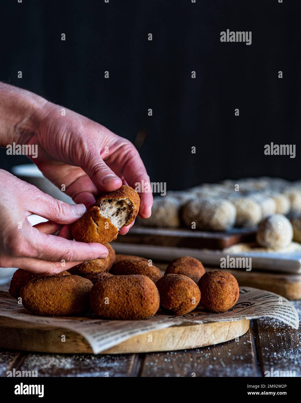 Crop anonyme personne prenant un morceau de croquette de joues de porc servi sur le panneau de bois sur la table Banque D'Images