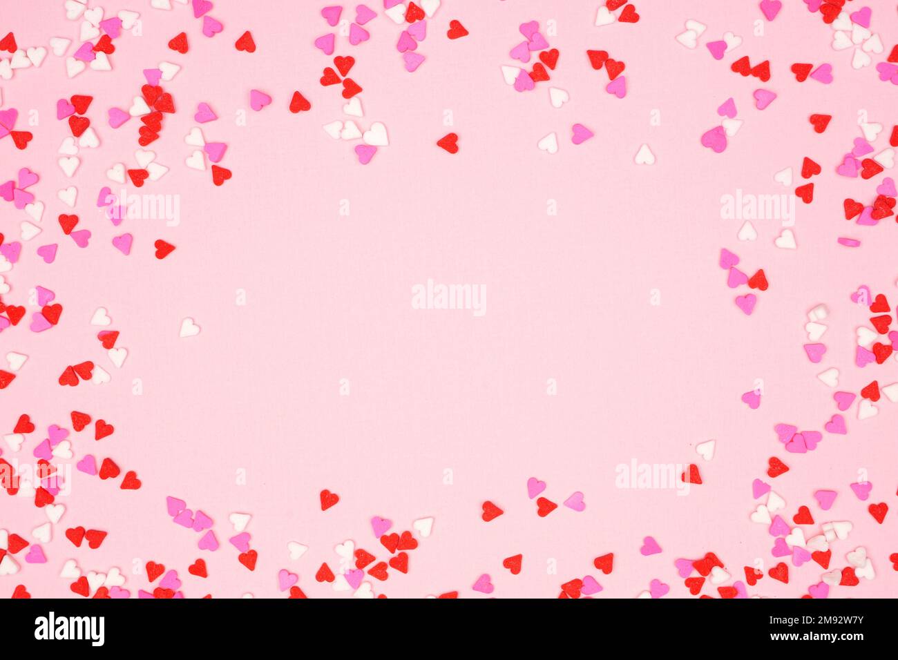 Saint-Valentin cadre de coeur de bonbons saupoudrer sur un fond rose texturé. Copier l'espace. Banque D'Images
