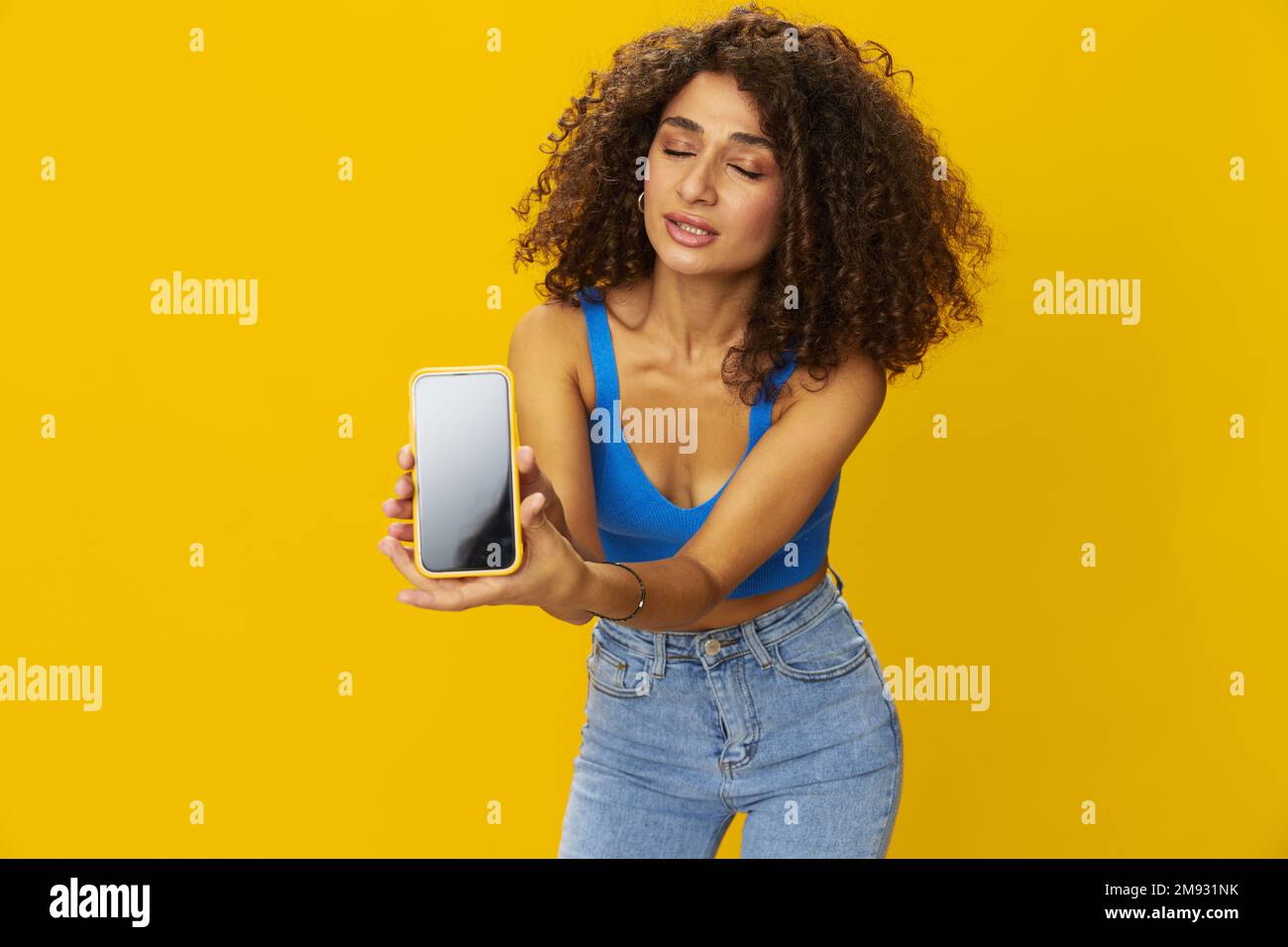 Influenceur femme avec le téléphone en main prenant des selfies parlant sur appel vidéo freelance travail de la technologie des médias sociaux, avec des cheveux frino maurly en chemise bleue Banque D'Images