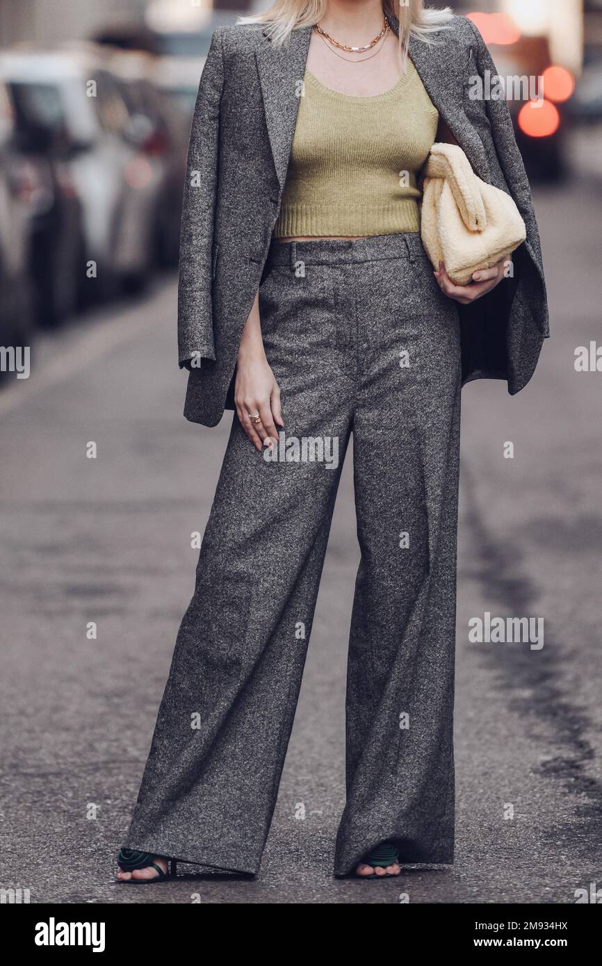 Milan, Italie - 25 février 2022: Femme en costume gris élégant avec haut jaune citron vert avec sac à Milan, Italie. Banque D'Images