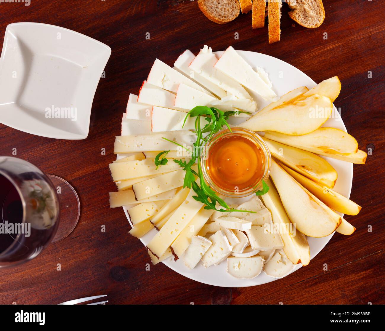 Assiette avec différents types de fromage et une tasse de miel Banque D'Images