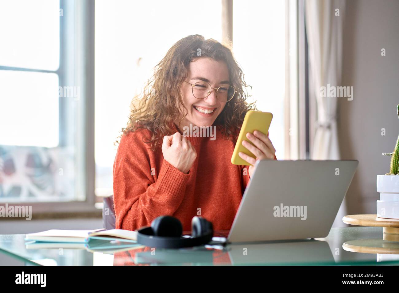 Jeune heureuse heureuse femme étudiante se sentant excitée gagnant regardant le téléphone portable. Banque D'Images