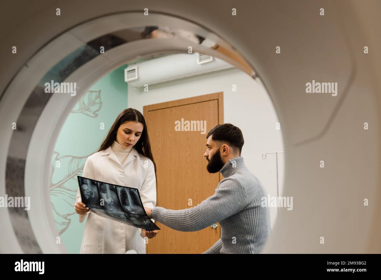 Le radiologue d'acquisition CT montre les rayons X de l'abdomen au patient dans la salle d'acquisition calculée. CT médecin consultant le patient et montrant les rayons X de la poitrine au patient Banque D'Images