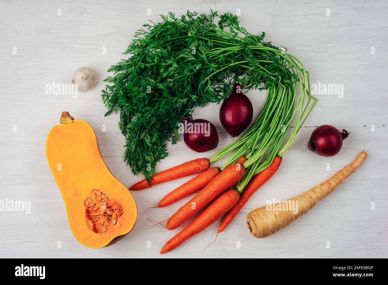Carottes aux légumes verts, courge musquée, panais, ail et oignon sur table en bois blanc