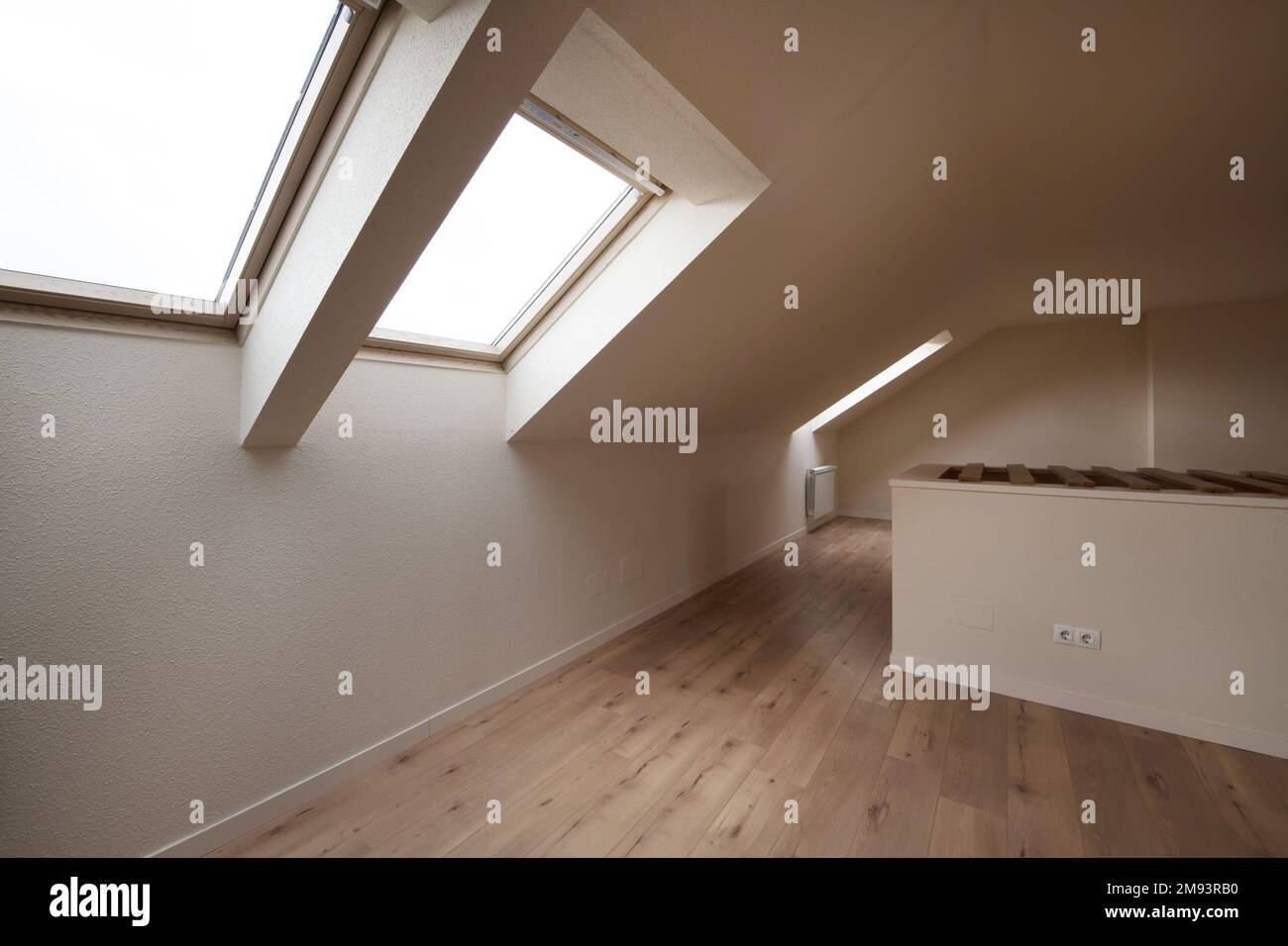 Chambre vide avec parquet en châtaignier et murs crème avec puits de lumière dans le plafond en pente Banque D'Images