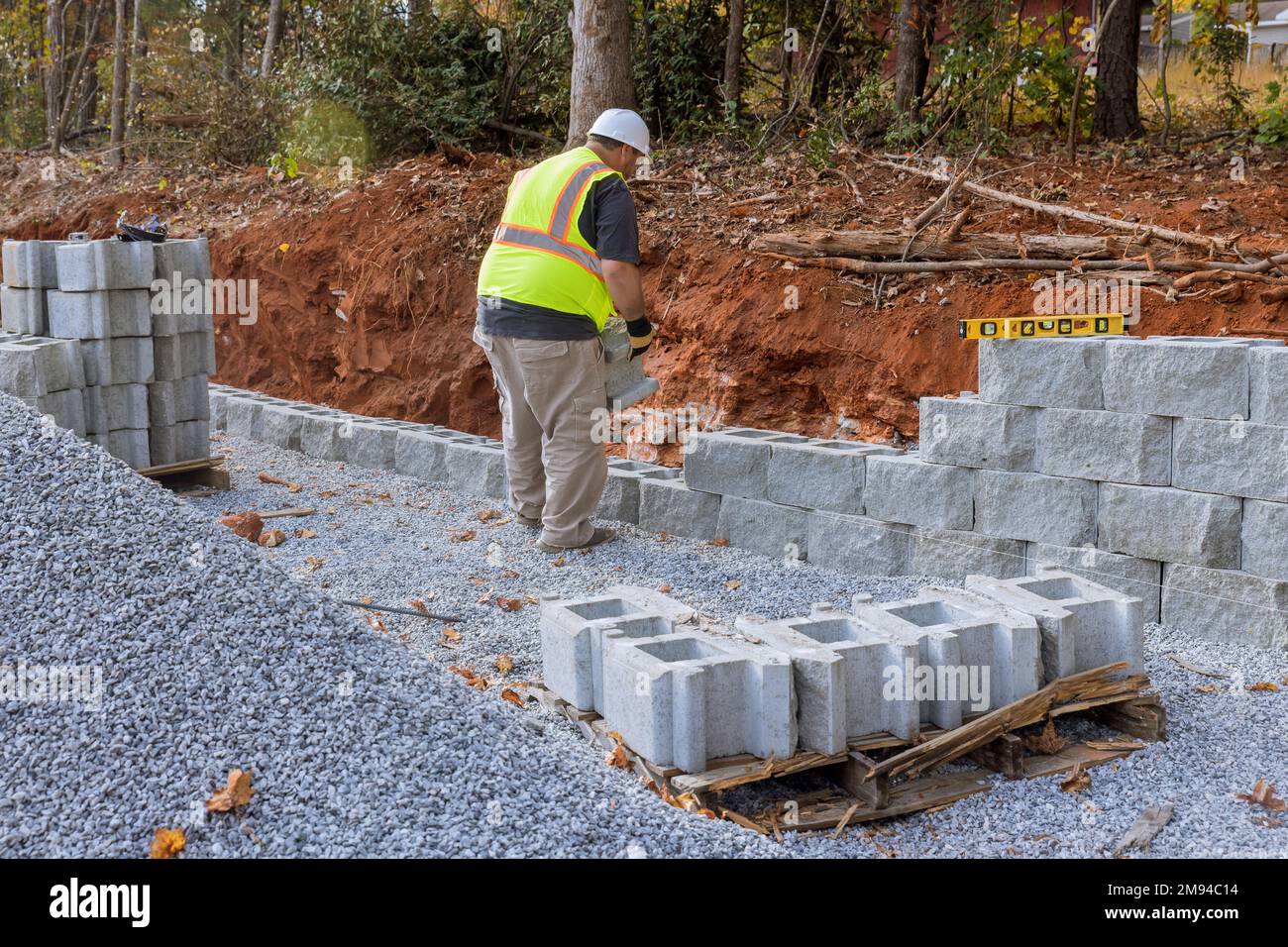 L'ouvrier de la construction installait des blocs de béton sur le chantier de construction près de la nouvelle maison comme partie construite du mur de soutènement Banque D'Images