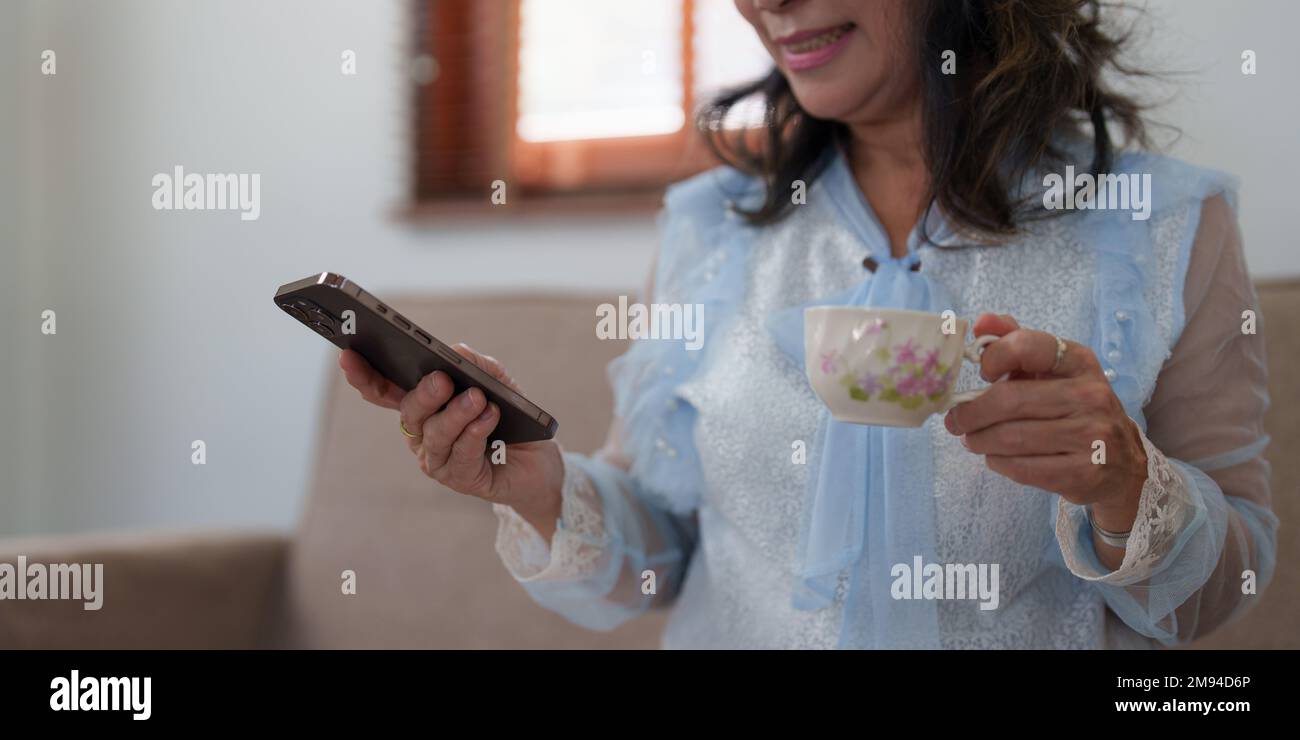 Smart asian mature femme d'affaires d'âge moyen chef de la direction professeur en utilisant le téléphone mobile, e-learning , travaillant à distance en ligne dans le bureau à domicile Banque D'Images