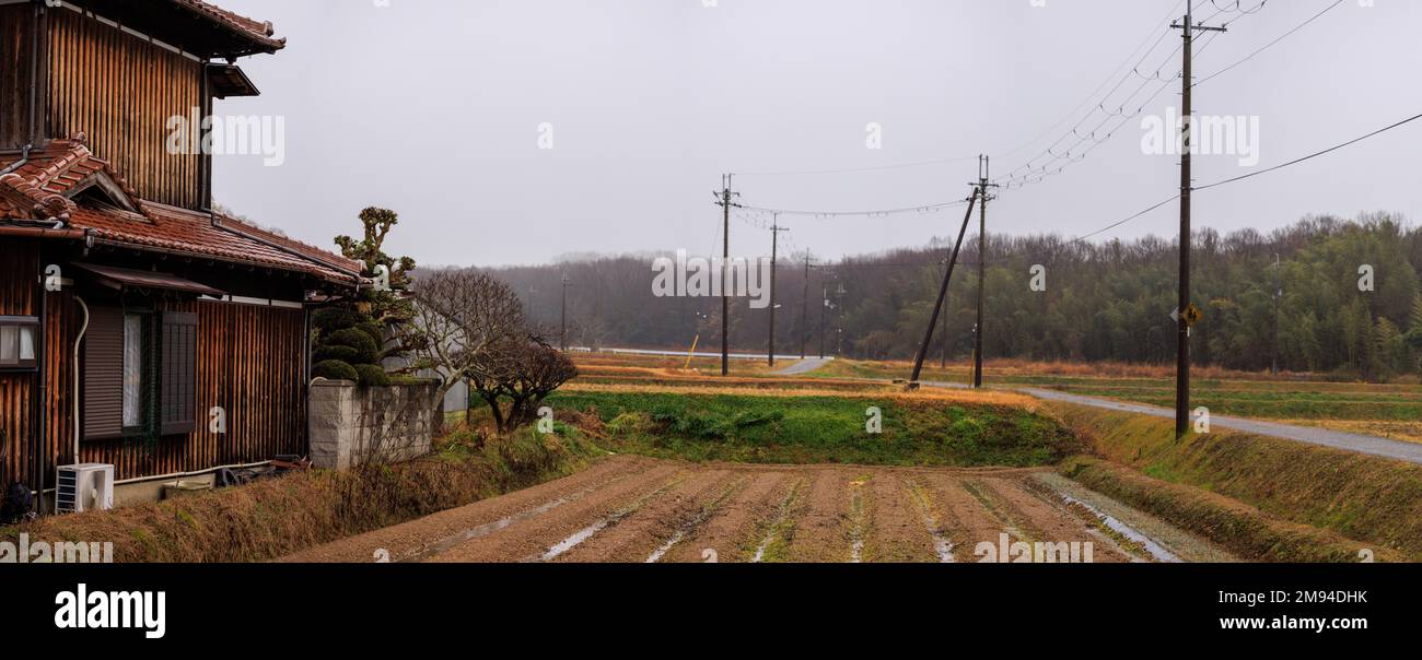 Ancienne maison japonaise en bois près de Small Rice Field et de la route de campagne le jour du Nuageux Banque D'Images