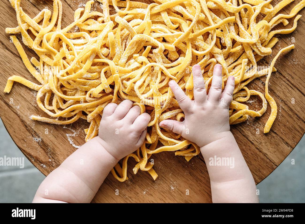 Pâtes et enfant. Bébé cuisine des pâtes fraîches italiennes dans la cuisine maison. Nourriture et enfants concept. Photo de haute qualité Banque D'Images