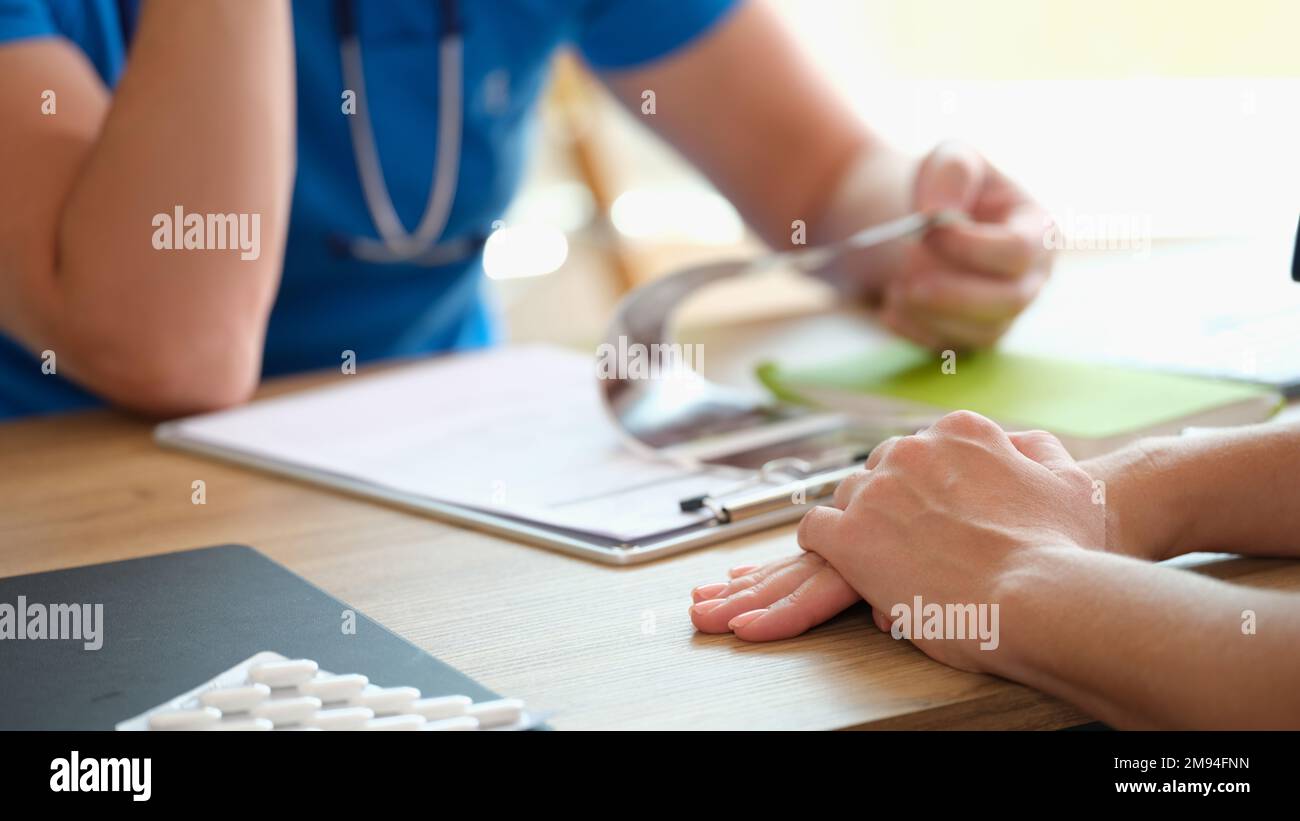 Médecin lisant le diagnostic du patient et examinant les résultats des tests médicaux sur son bureau. Banque D'Images
