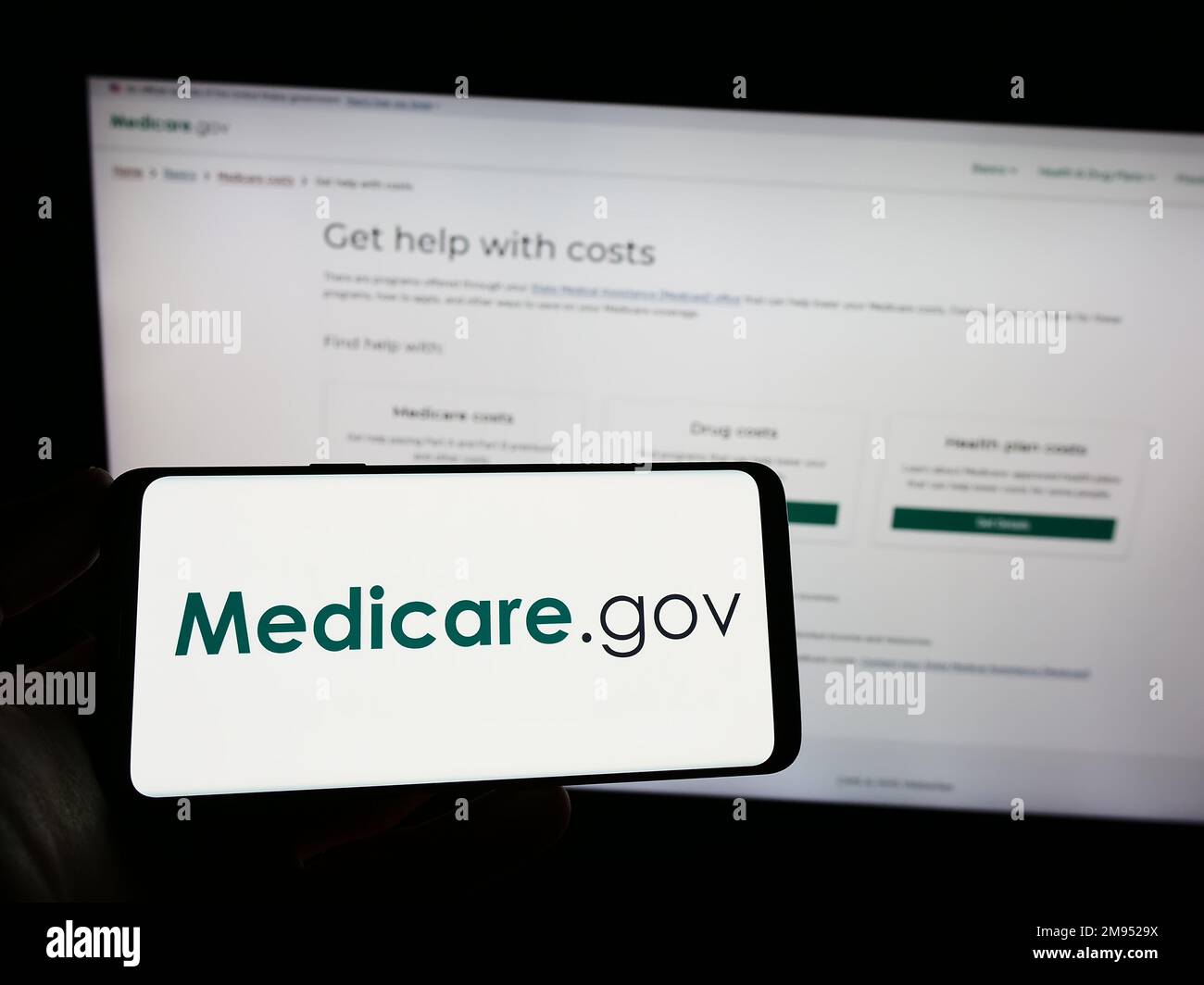 Personne tenant un smartphone avec le logo du programme américain d'assurance maladie Medicare à l'écran devant le site Web. Mise au point sur l'affichage du téléphone. Banque D'Images