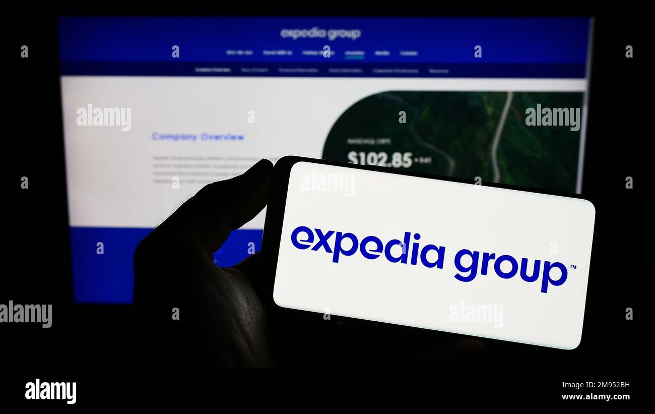 Personne tenant un téléphone portable avec le logo de la société américaine de voyages en ligne Expedia Group Inc. À l'écran devant la page Web. Mise au point sur l'affichage du téléphone. Banque D'Images