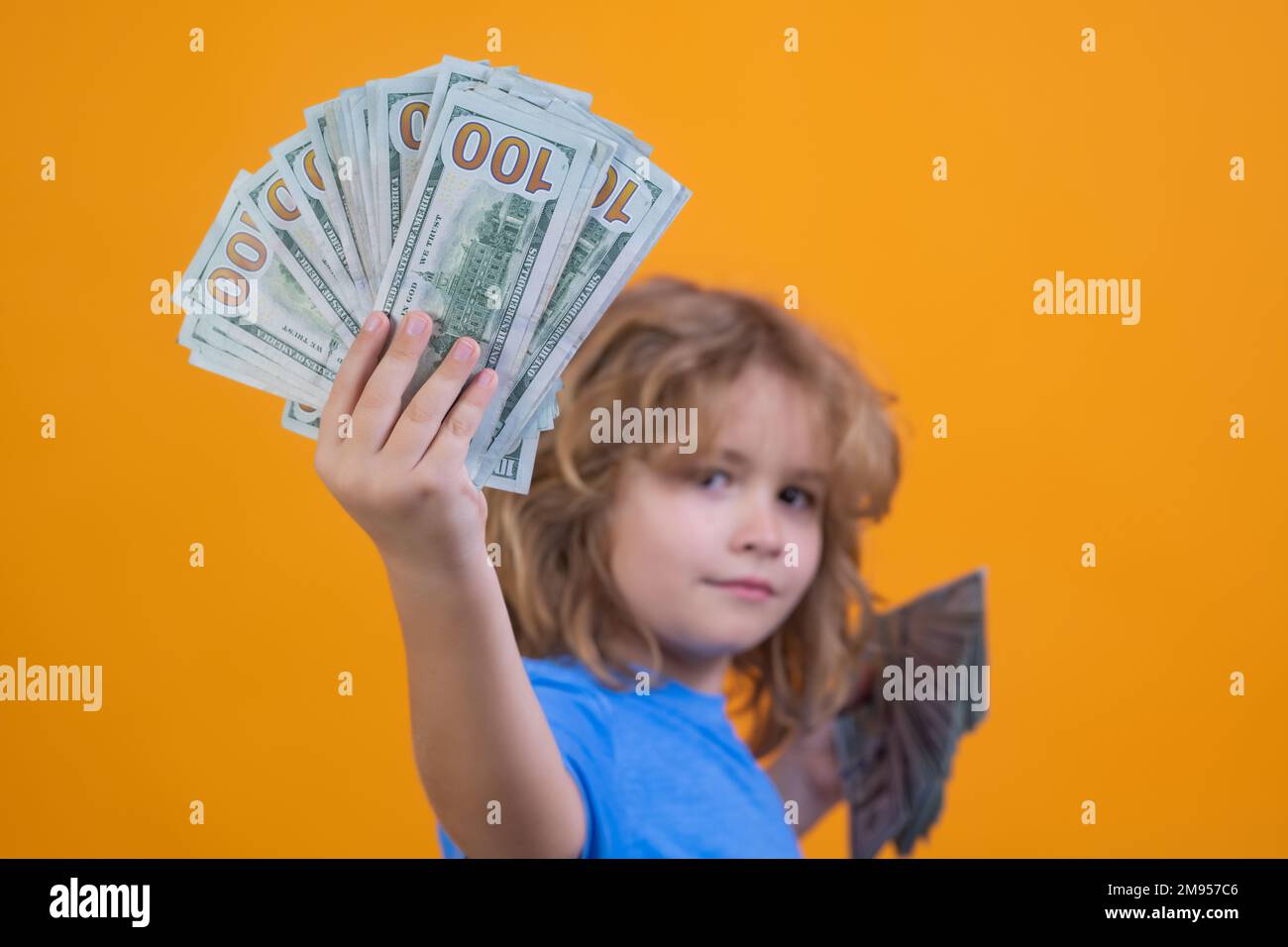 Enfant avec beaucoup d'argent billets de dollars isolés sur fond jaune studio. Banque D'Images