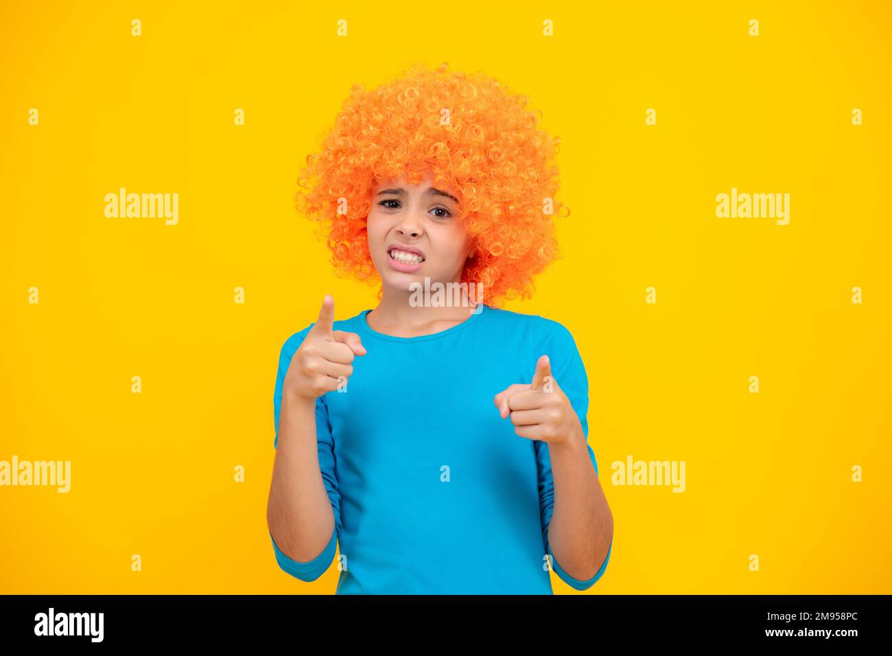 Fête d'anniversaire pour filles. Drôle d'enfant dans la perruque rouge curly. Temps de Amuse-toi bien. Jeune fille avec des cheveux orange, étant un clown. Visage en colère, émotions bouleversées de teena Banque D'Images