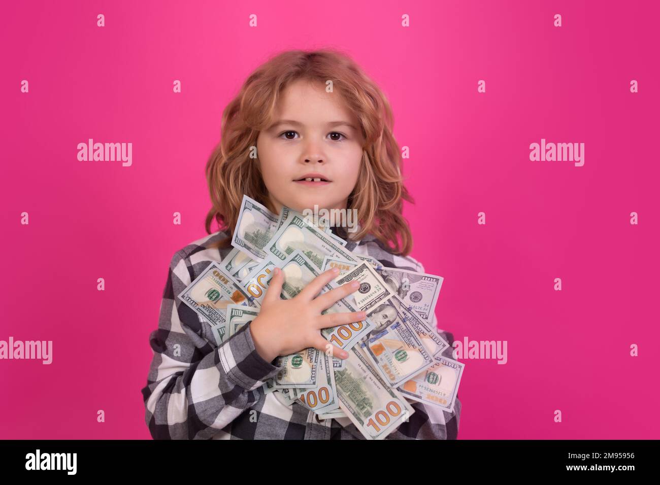 Enfant montrant des billets d'argent dollar, debout rêveur de riche contre arrière-plan isolé de studio rouge rose. Banque D'Images
