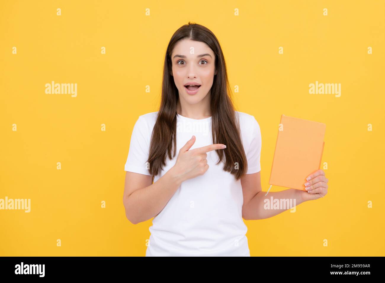 Drôle surpris jeune fille avec des blocs-notes debout sur fond jaune avec l'espace de copie. Concept éducatif pour l'école. Portrait du jeune étudiant. Banque D'Images