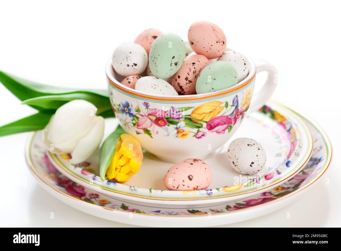 Pâques gâte le chocolat sucré oeufs de Pâques dans un bol sur l'assiette autour des fleurs de printemps et des décorations de fête. Réglage de la table de Pâques. Banque D'Images