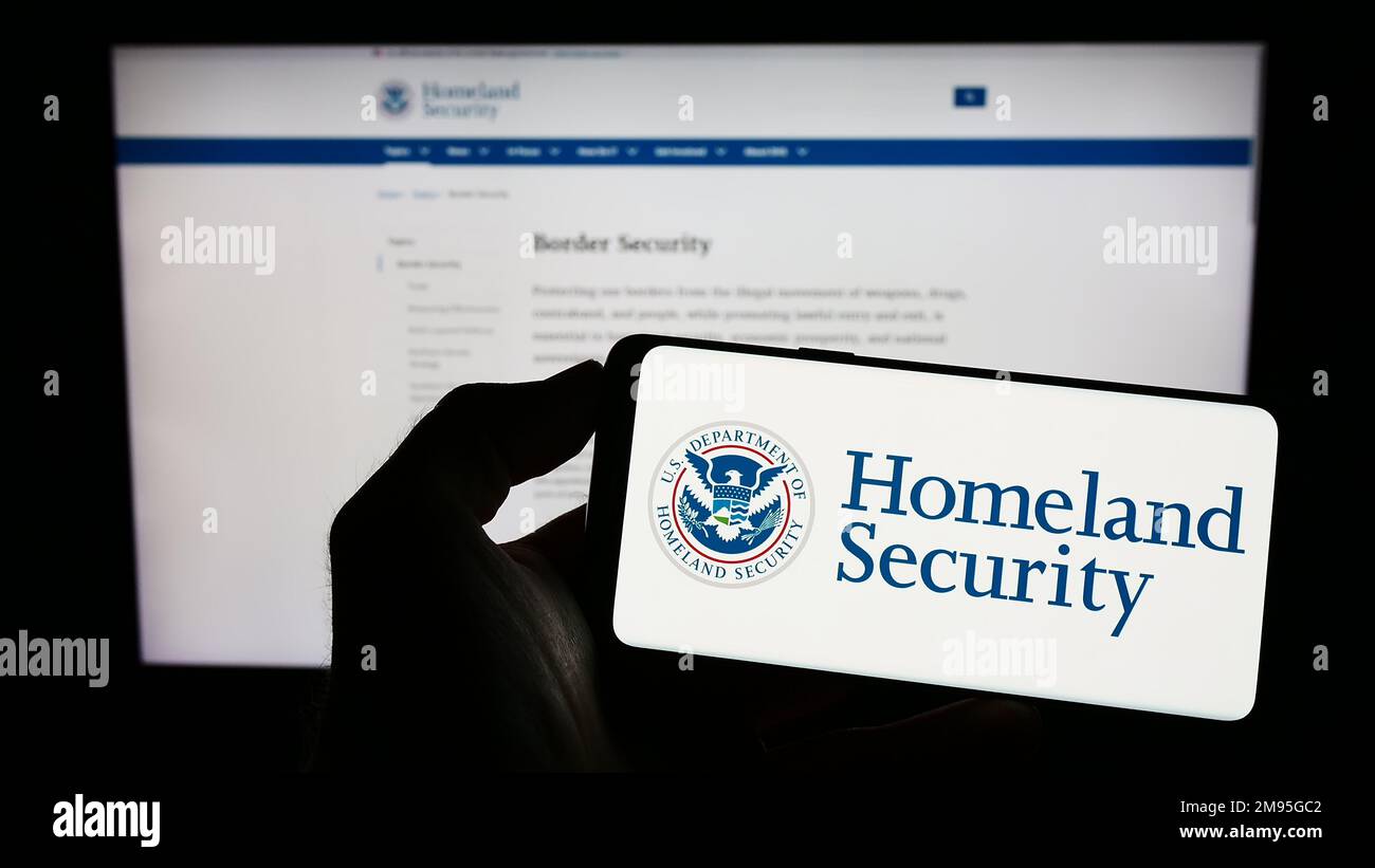 Personne tenant un smartphone portant le sceau du département américain de la sécurité intérieure (DHS) à l'écran devant le site Web. Mise au point sur l'affichage du téléphone. Banque D'Images