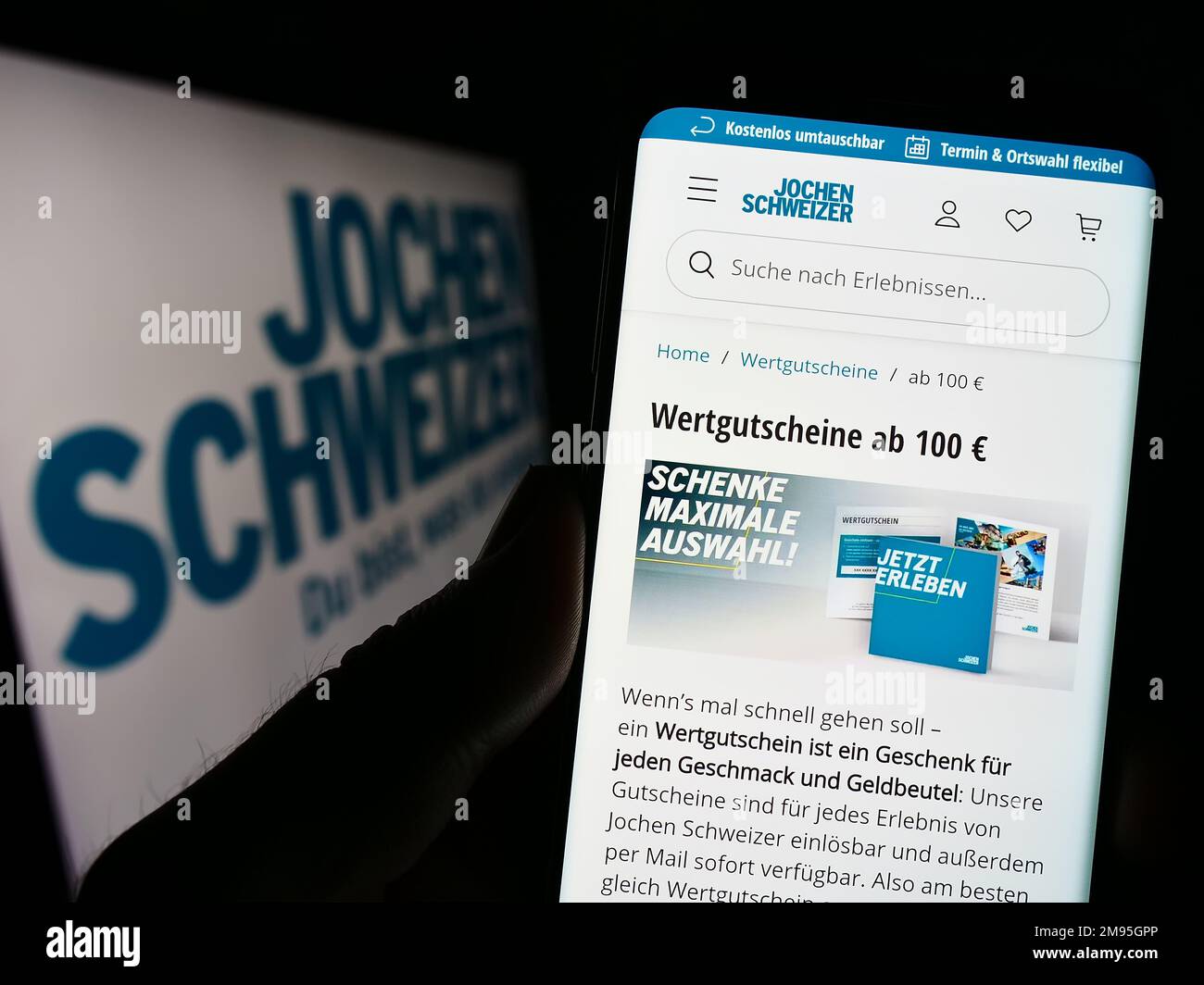 Personne tenant un téléphone portable avec la page web de la société allemande Jochen Schweizer GmbH sur l'écran devant le logo. Concentrez-vous sur le centre de l'écran du téléphone. Banque D'Images