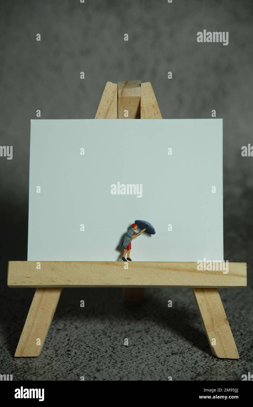 Photographie miniature de personnage de jouet de personnes. Femmes debout au-dessus de pied en bois sur le calendrier de bureau vierge. Fond gris nuageux. Photo d'image Banque D'Images