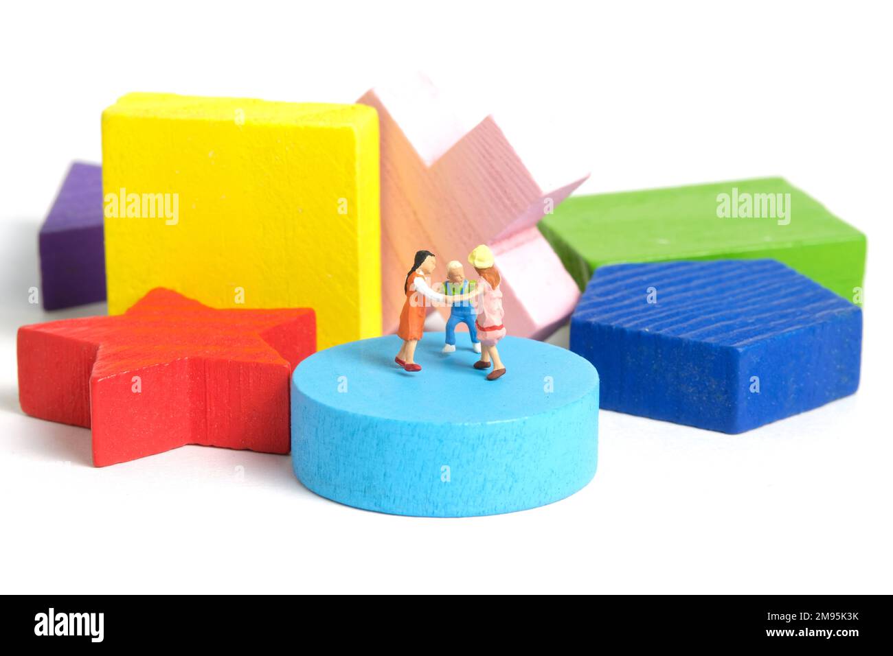 Photographie miniature de personnage de jouet de personnes. Concept d'apprentissage amusant. Les enfants jouent ensemble au-dessus du puzzle en bois Montessori. Isolé sur fond blanc. Image Banque D'Images