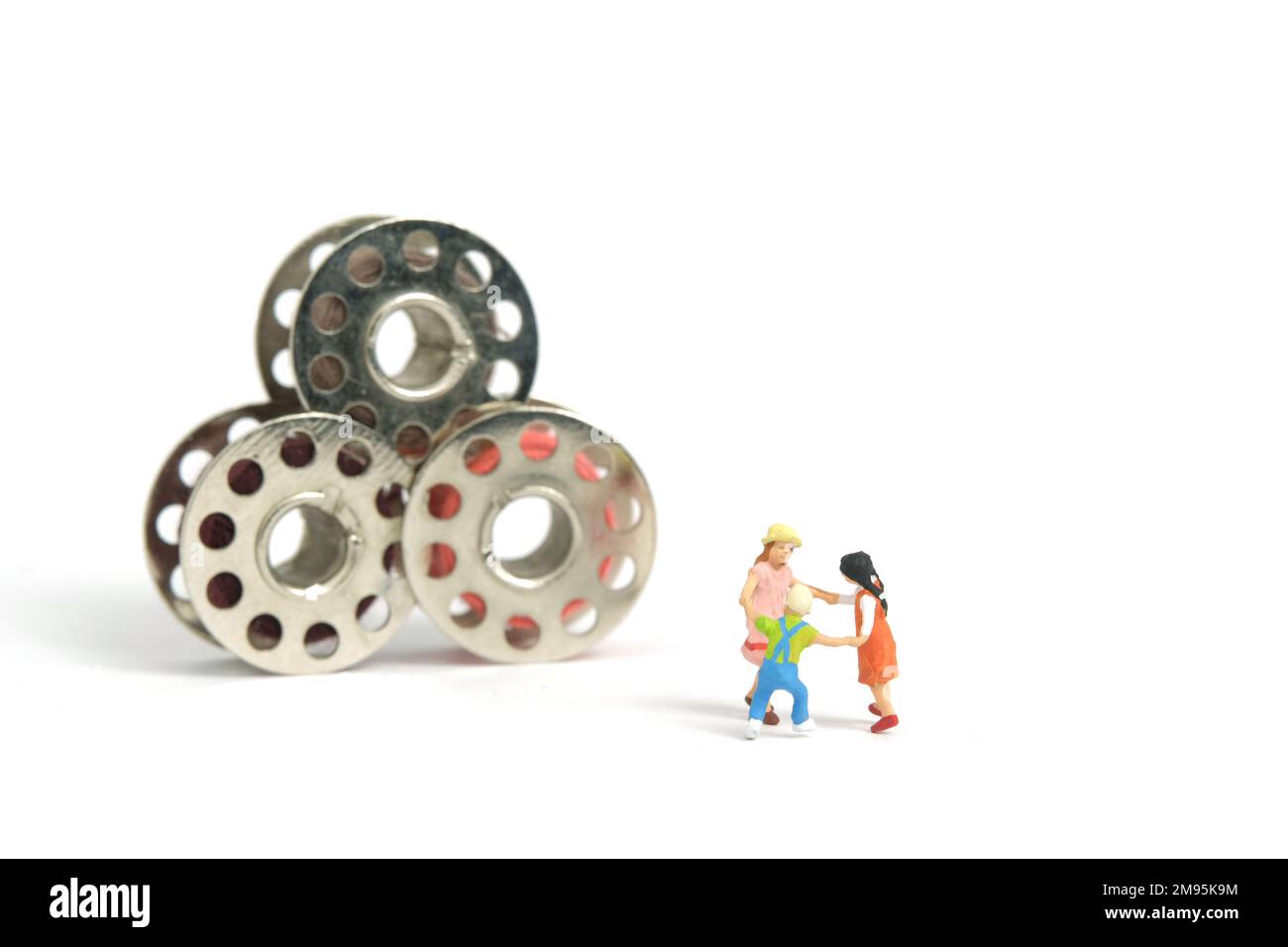 Photographie miniature de personnage de jouet de personnes. Concept d'arène de jeux. Enfants jouant ensemble dans la bobine de fil de couture. Isolé sur fond blanc. IMA Banque D'Images