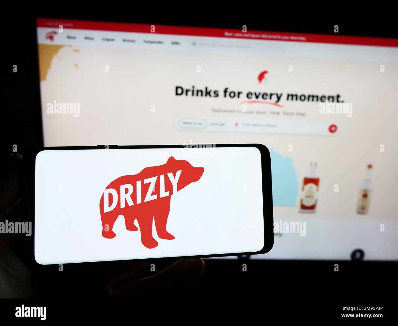 Personne tenant un smartphone avec le logo de la société américaine de livraison d'alcool Drizly LLC sur l'écran devant le site Web. Mise au point sur l'affichage du téléphone. Banque D'Images