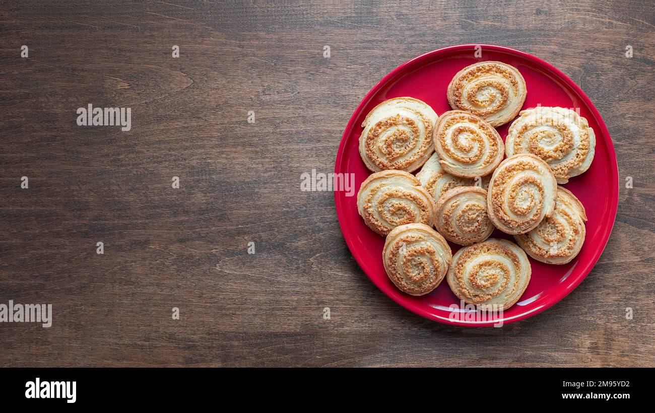 Biscuits en spirale de sucre sur la plaque rouge sur la table en bois, bannière avec espace de copie. Petits gâteaux ronds faits maison, vue de dessus. Concept de pâtisserie Banque D'Images