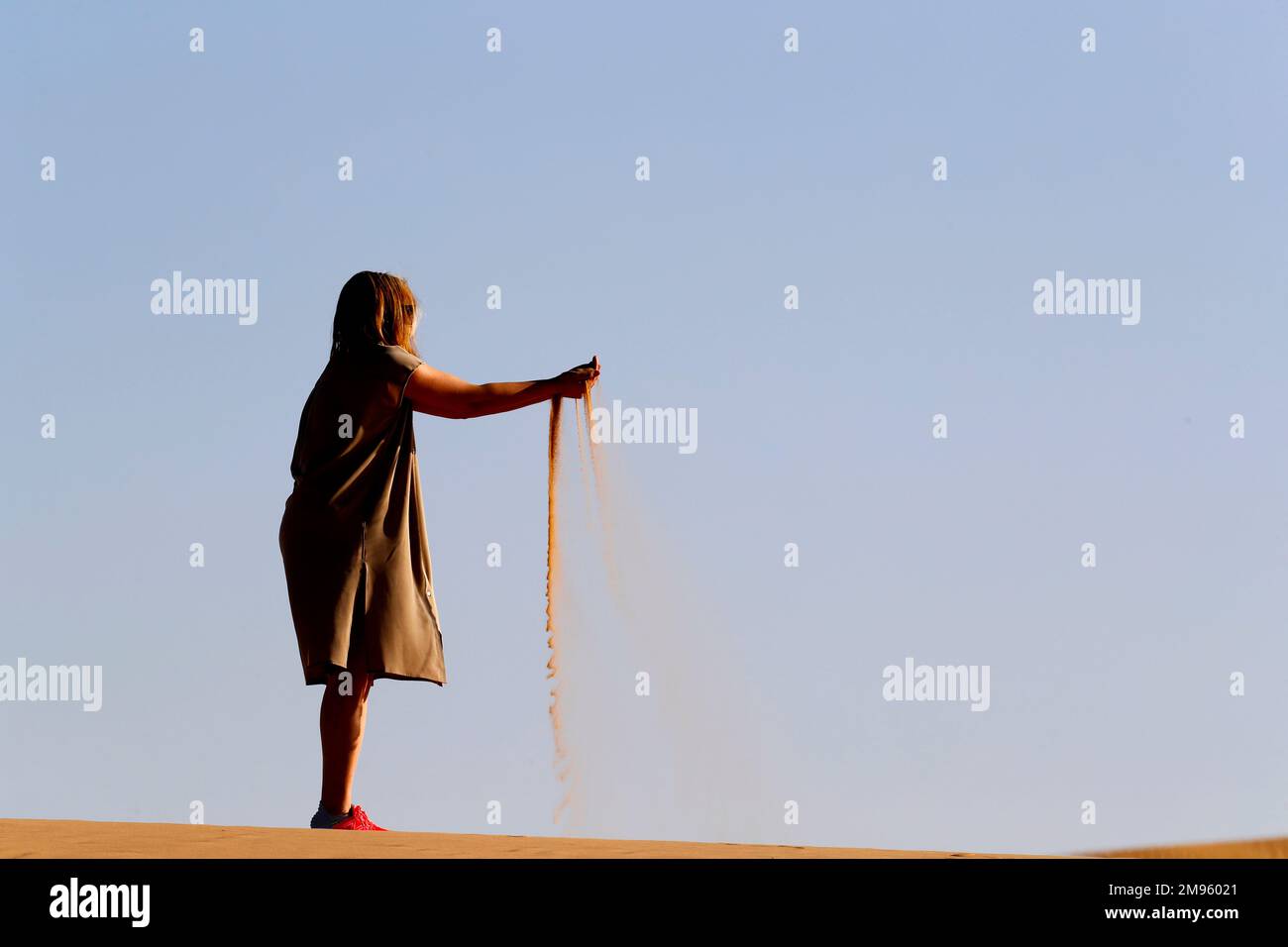 Femme avec du sable entre les mains dans le désert arabe. Émirats arabes Unis. Banque D'Images