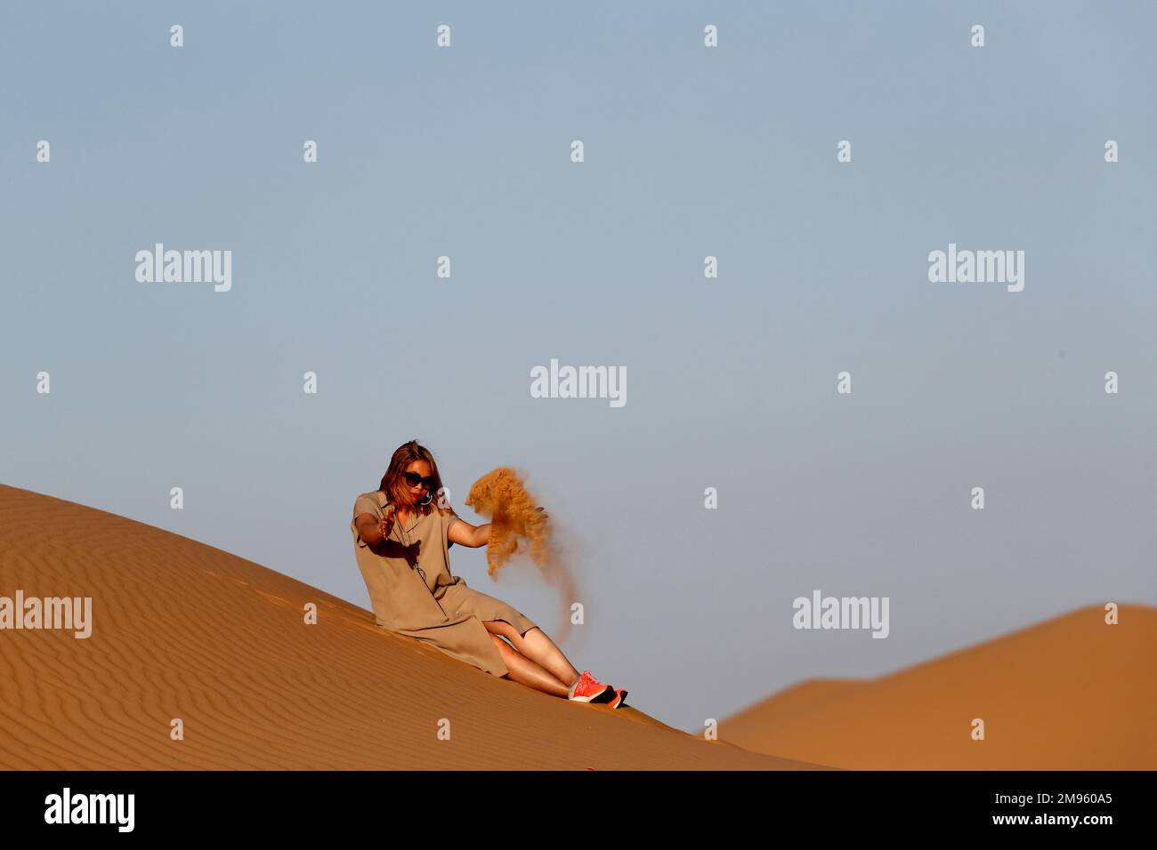 Femme assise seule sur une dune de sable vers le désert arabe. Émirats arabes Unis. Banque D'Images
