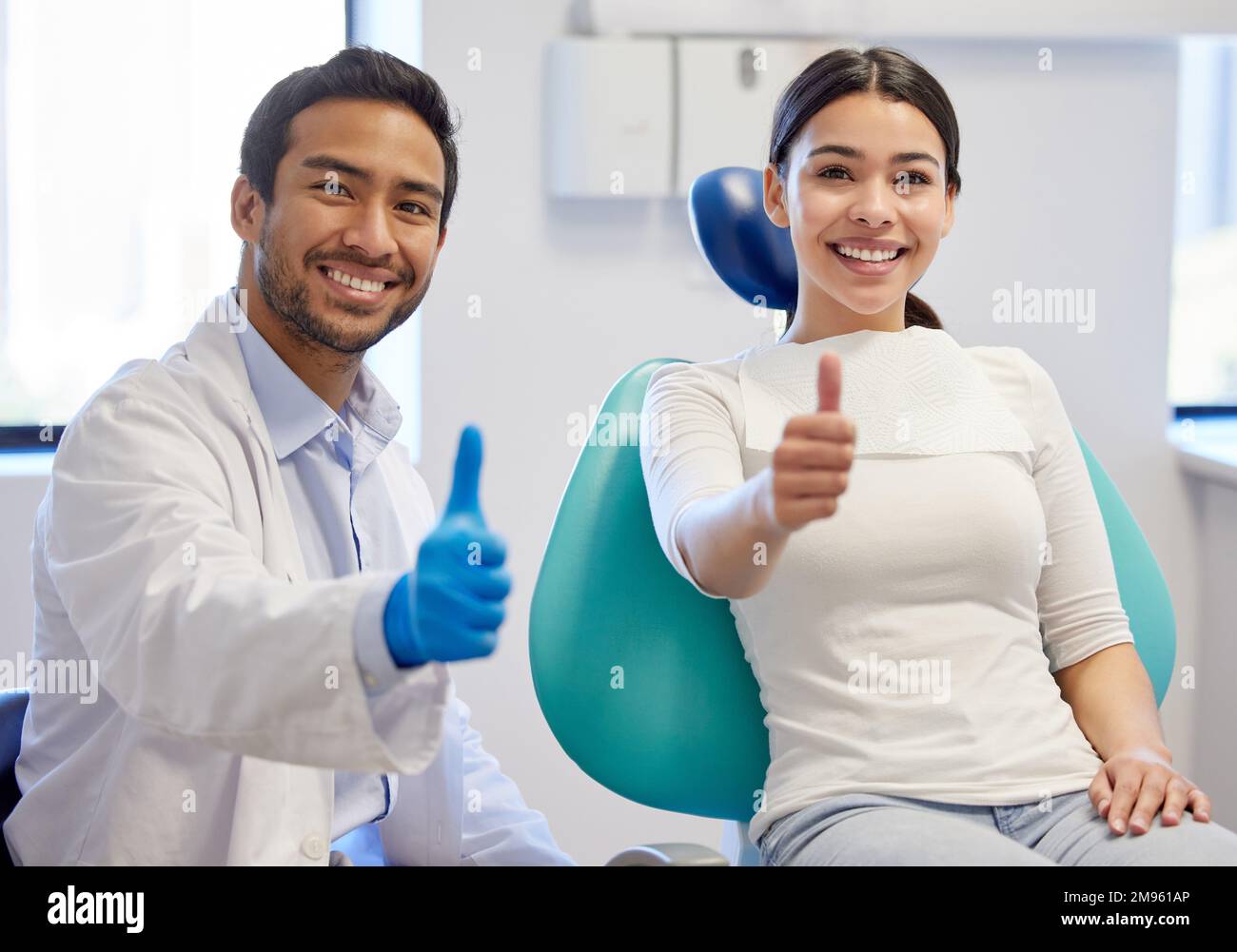 Réservez votre place avec le meilleur dans le secteur dentaire. Portrait d'une jeune femme montrant les pouces vers le haut tout en visitant le dentiste. Banque D'Images