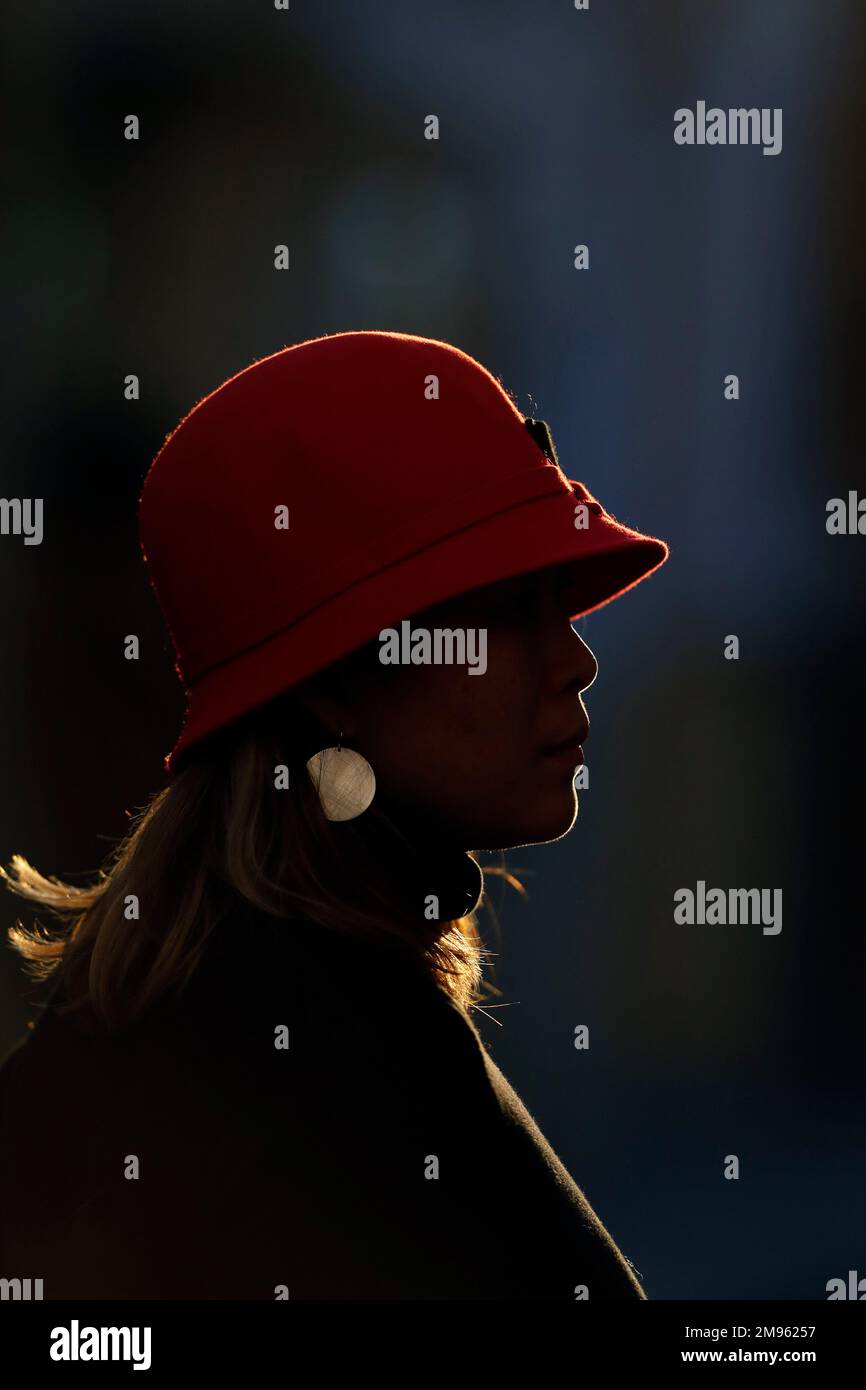 Vue de profil de la femme silhouette portant un rouge debout à l'extérieur pendant le coucher du soleil. Banque D'Images