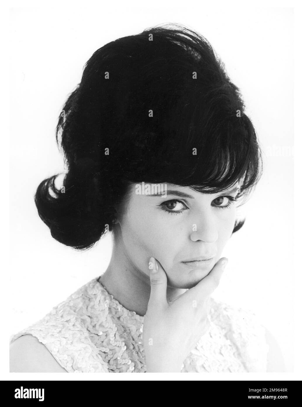 Femme aux cheveux foncés avec sa main sur son menton en train de regarder plutôt triste. Banque D'Images