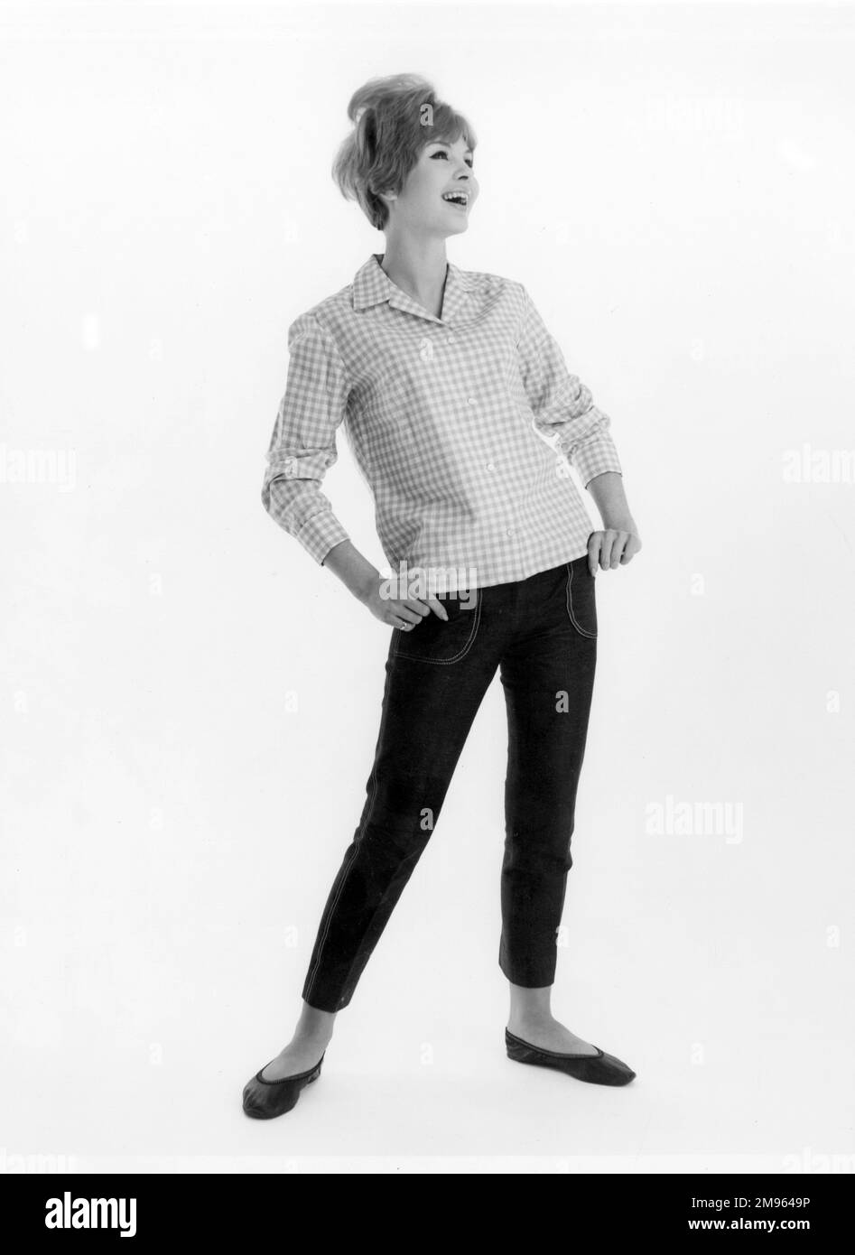 Portrait sur toute la longueur d'un modèle dans une chemise à carreaux et un Jean court, posant pour l'appareil photo. Banque D'Images