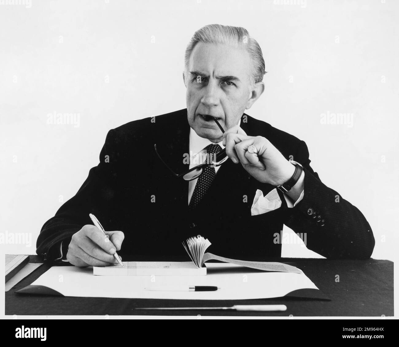 Un homme s'assoit à son bureau avec son livre de chèque. Banque D'Images