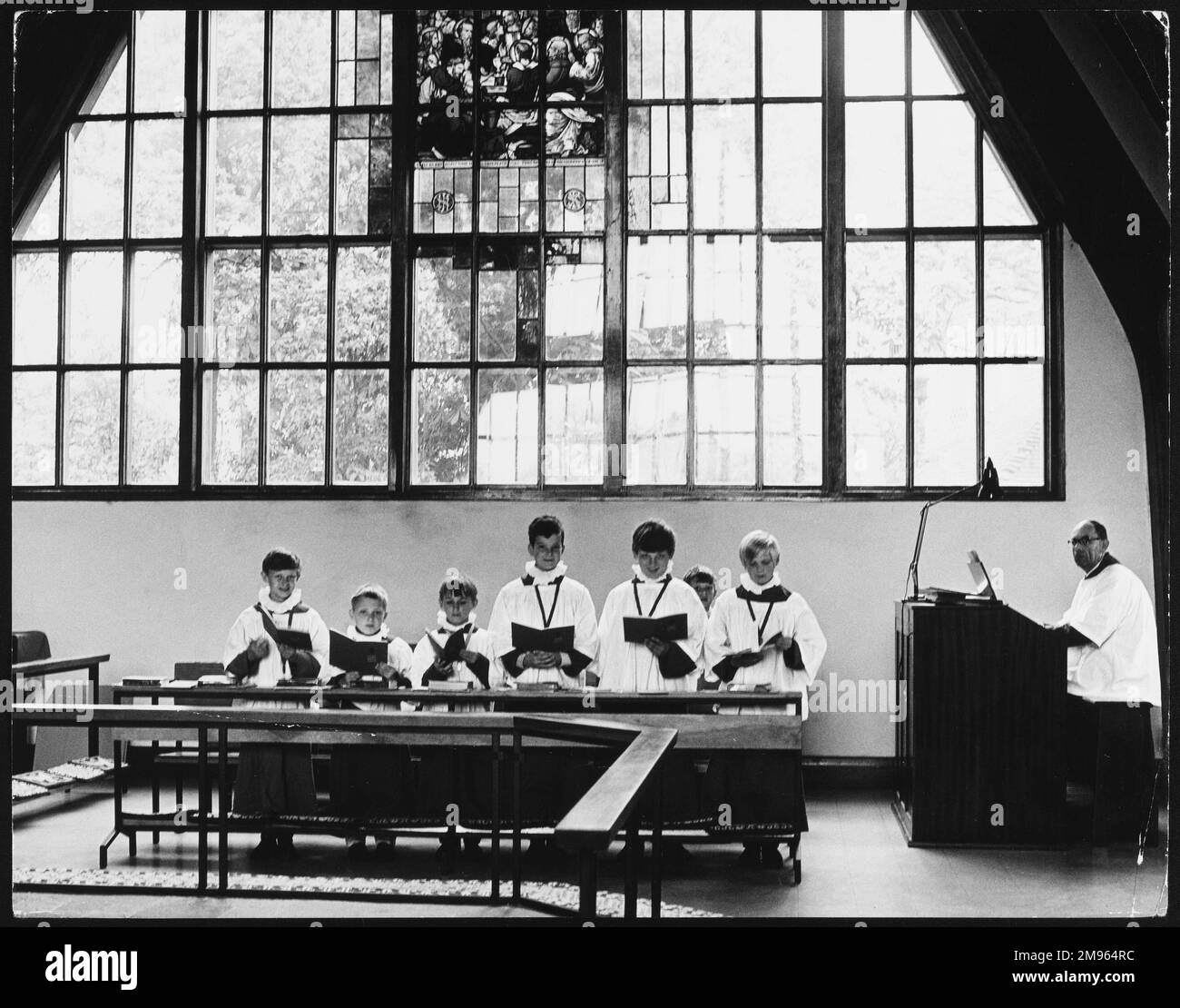 Choirboys chantant sous un vitrail à l'église Salfords, Horley, Surrey, Angleterre. Banque D'Images