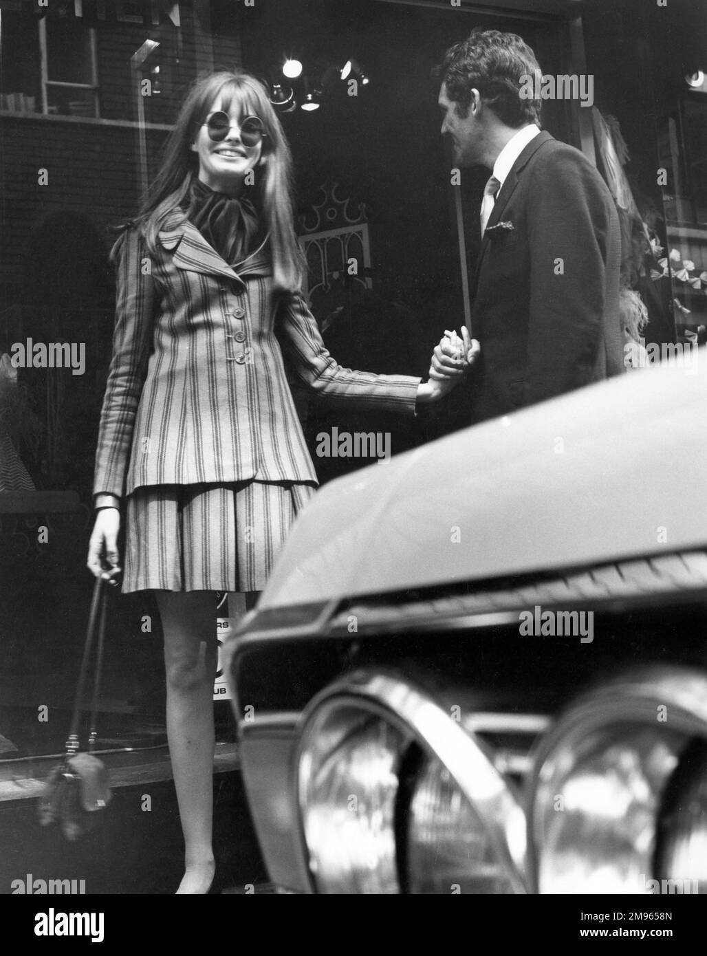 Un couple bien habillé magasiner sur Carnaby Street, le centre branché de Londres balançoire. Banque D'Images