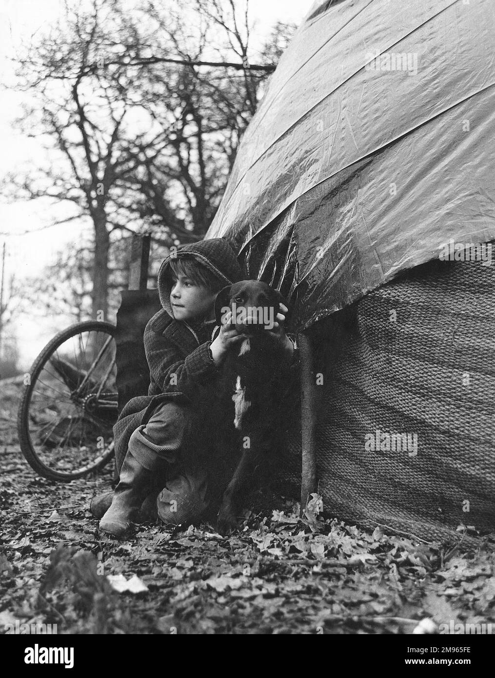 Un enfant gitan ardu, qui câlin un chien noir et blanc. Banque D'Images