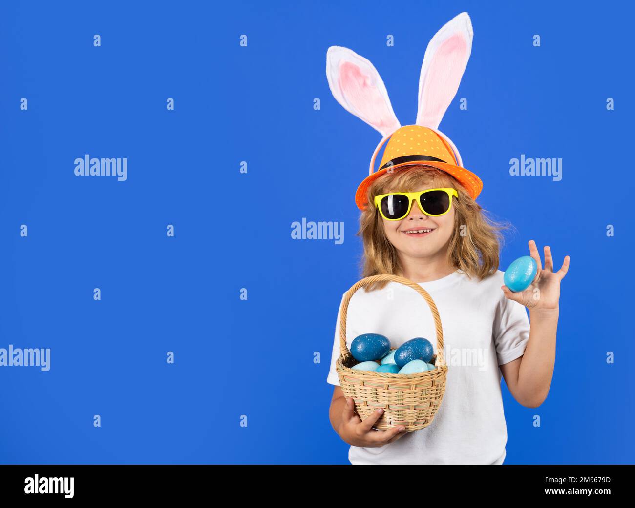 Vacances de Pâques, chasse aux lapins. Enfant avec oreilles de lapin tenant le panier de pâques. Enfant garçon avec œufs de pâques. Studio portrait isolé pour enfants. Banque D'Images