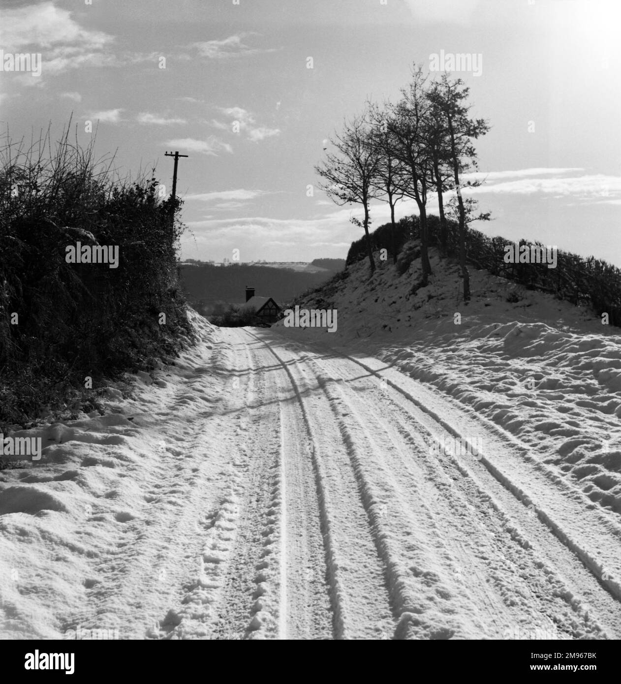 Une voie de campagne enneigée, des pistes dans la neige donnant des preuves au passage de plusieurs véhicules à moteur. Photographie de Norman Synge Waller Budd Banque D'Images