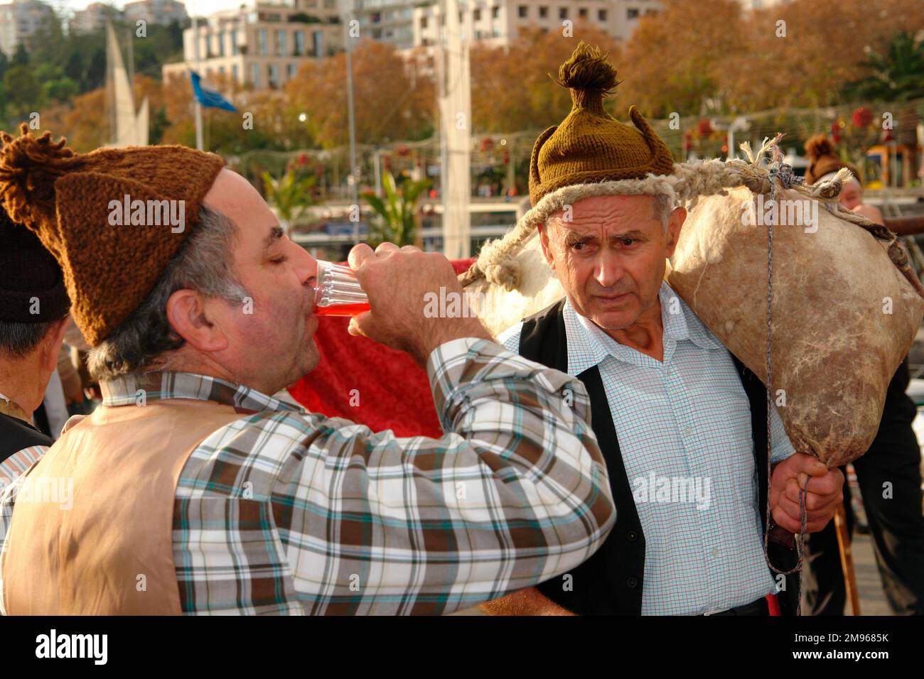 Deux hommes appartenant à un groupe folklorique de Porto da Cruz, prenant part au divertissement de rue à Funchal, la capitale de Madère. L'homme de droite porte du vin dans un wineskin au-dessus de son épaule, tandis que l'homme de gauche aime une gorgée rapide. Banque D'Images