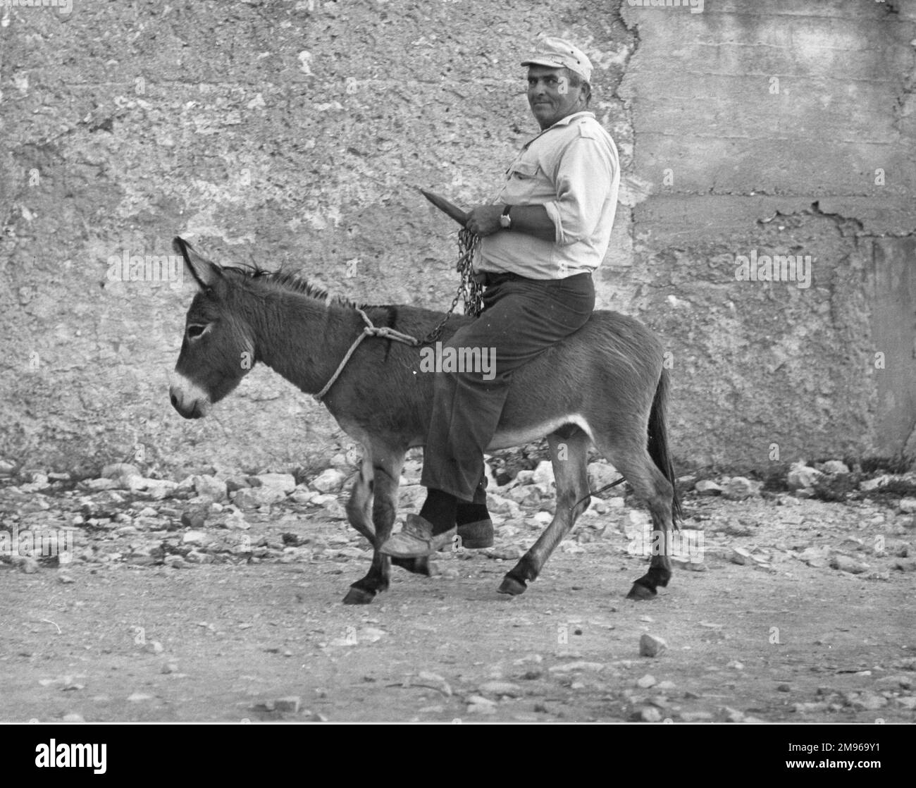 Un homme à cheval sur un petit âne qui est peut-être plus petit qu'il ne l'est! Banque D'Images