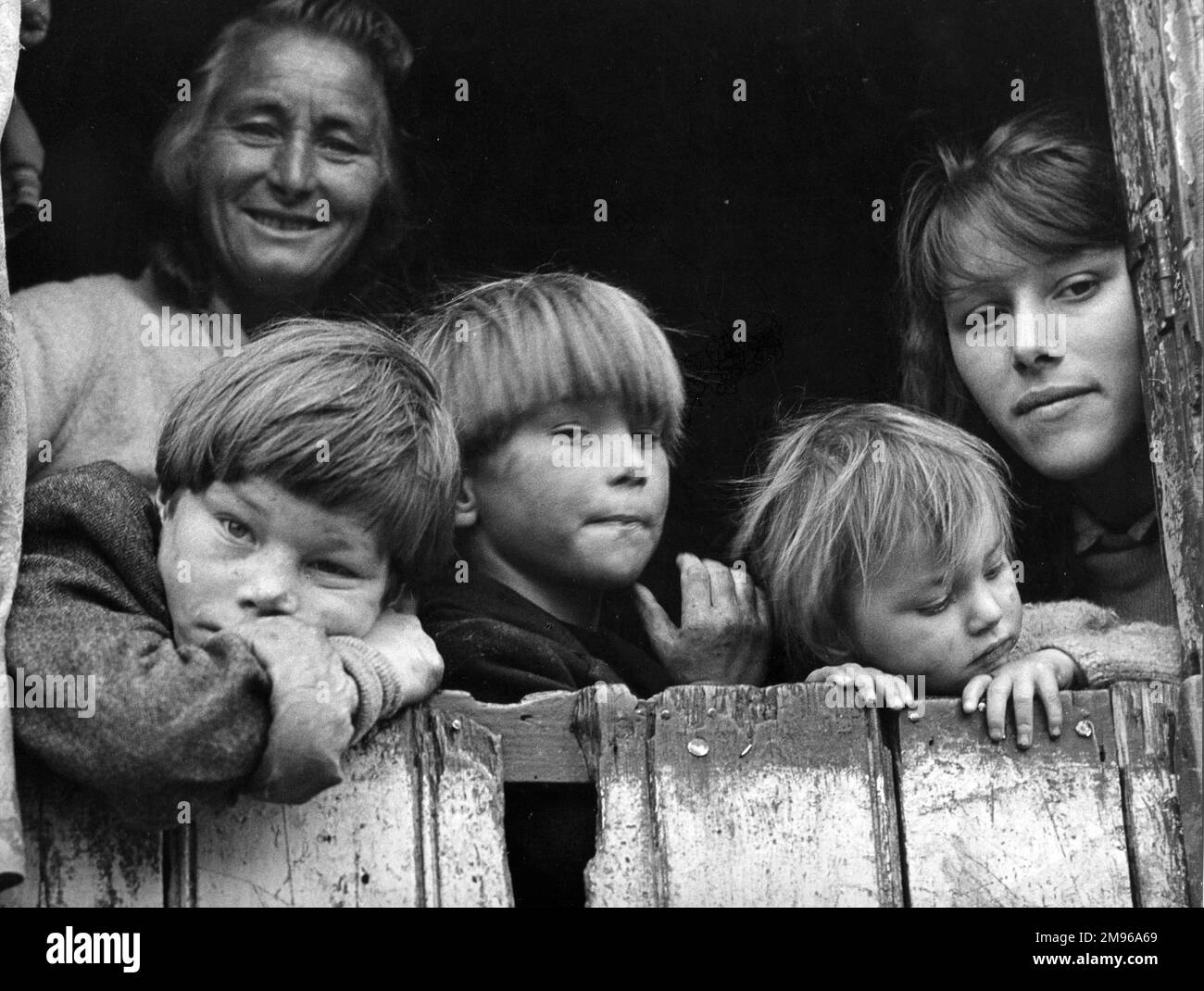 Les membres d'une famille tzigane -- deux femmes et trois garçons -- regardant par l'arrière de leur caravane dans un campement à Surrey. Banque D'Images