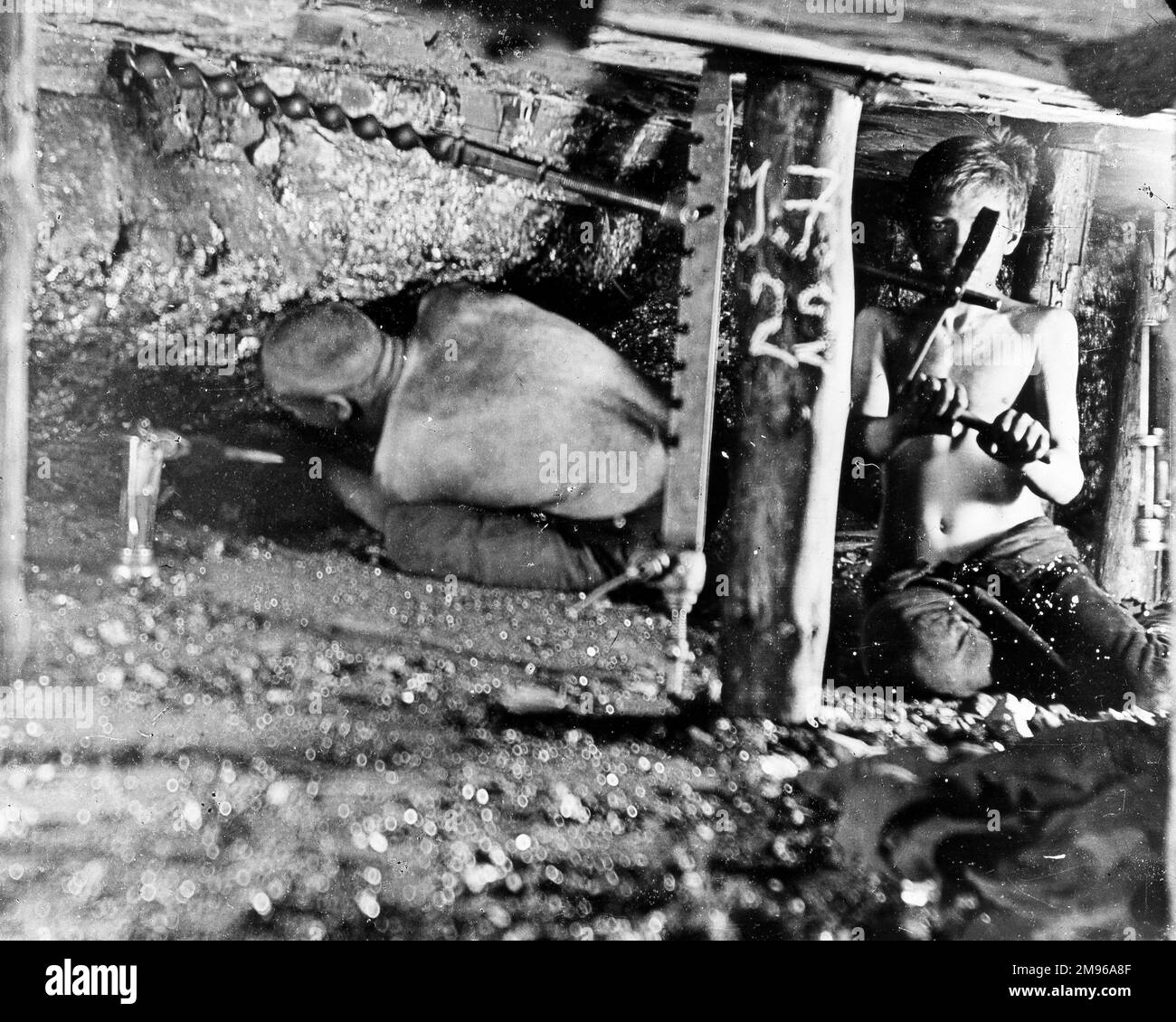 Deux mineurs, dont un très jeune, travaillent dans une étroite veine de charbon dans une mine du sud du pays de Galles. Banque D'Images