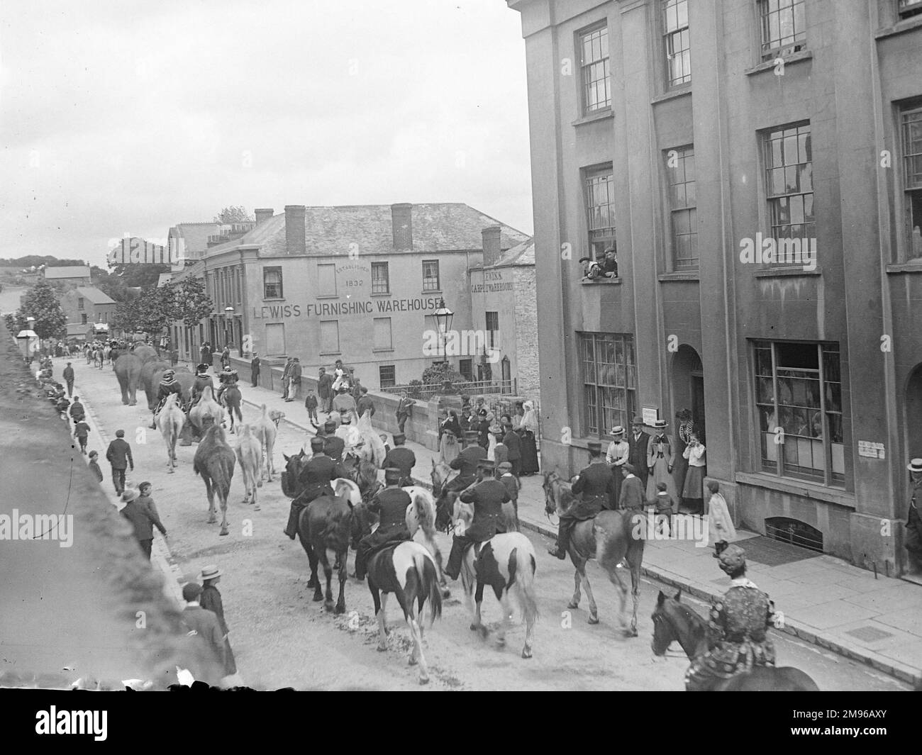 Le cirque parades le long de New Bridge à Haverfordwest, Pembrokeshire, Dyfed, au sud du pays de Galles, avec des éléphants, chameaux et chevaux. Les habitants de la ville s'arrêtent et regardent, et certains suivent la parade le long de la chaussée. Lewis's Furnishing Warehouse peut être vu dans l'arrière-plan. Banque D'Images