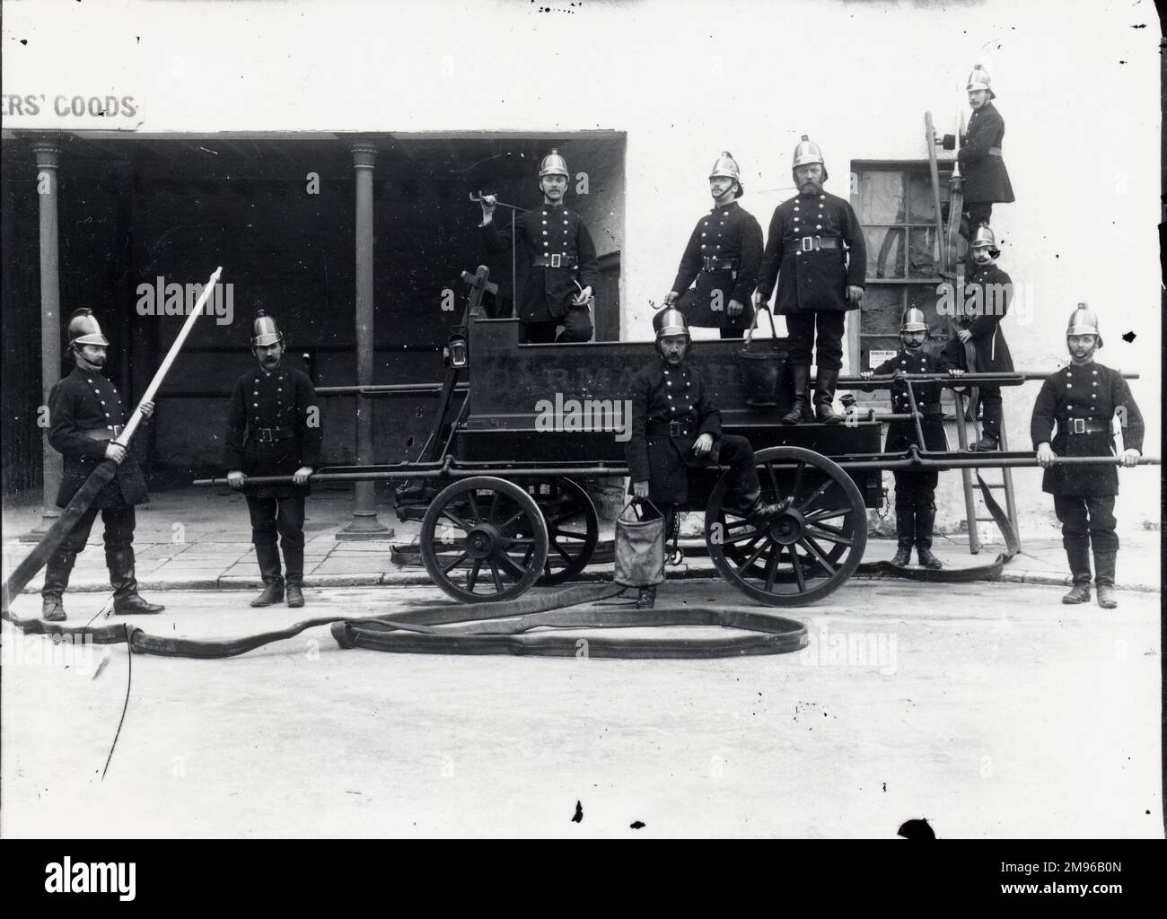 Dix membres de l'équipage de feu de Carmarthen posent pour leur photographie à l'extérieur de Cooperss' Goods à Carmarthen, la ville de comté de Carmarthenshire, Dyfed, au sud du pays de Galles. Ils sont en uniforme, avec leur moteur d'incendie et une échelle, et démontrent l'utilisation des hosepipes. Banque D'Images