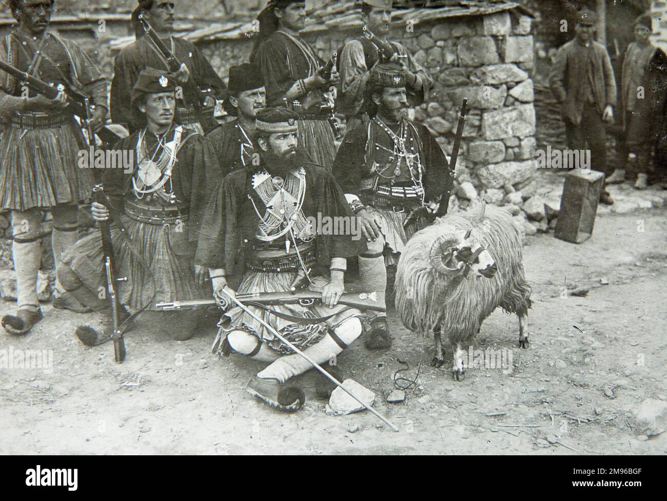 Un groupe de soldats albanais en costume traditionnel, avec fusils. Leur mascotte, un bélier, se tient à côté. Banque D'Images