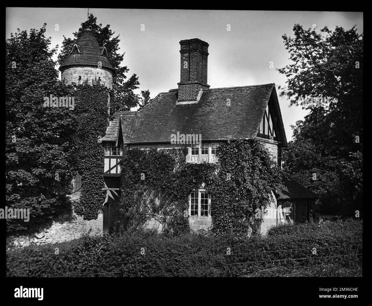 Une ancienne maison en pierre surcultivée avec de l'ivy, avec une tour circulaire sur la gauche. Banque D'Images