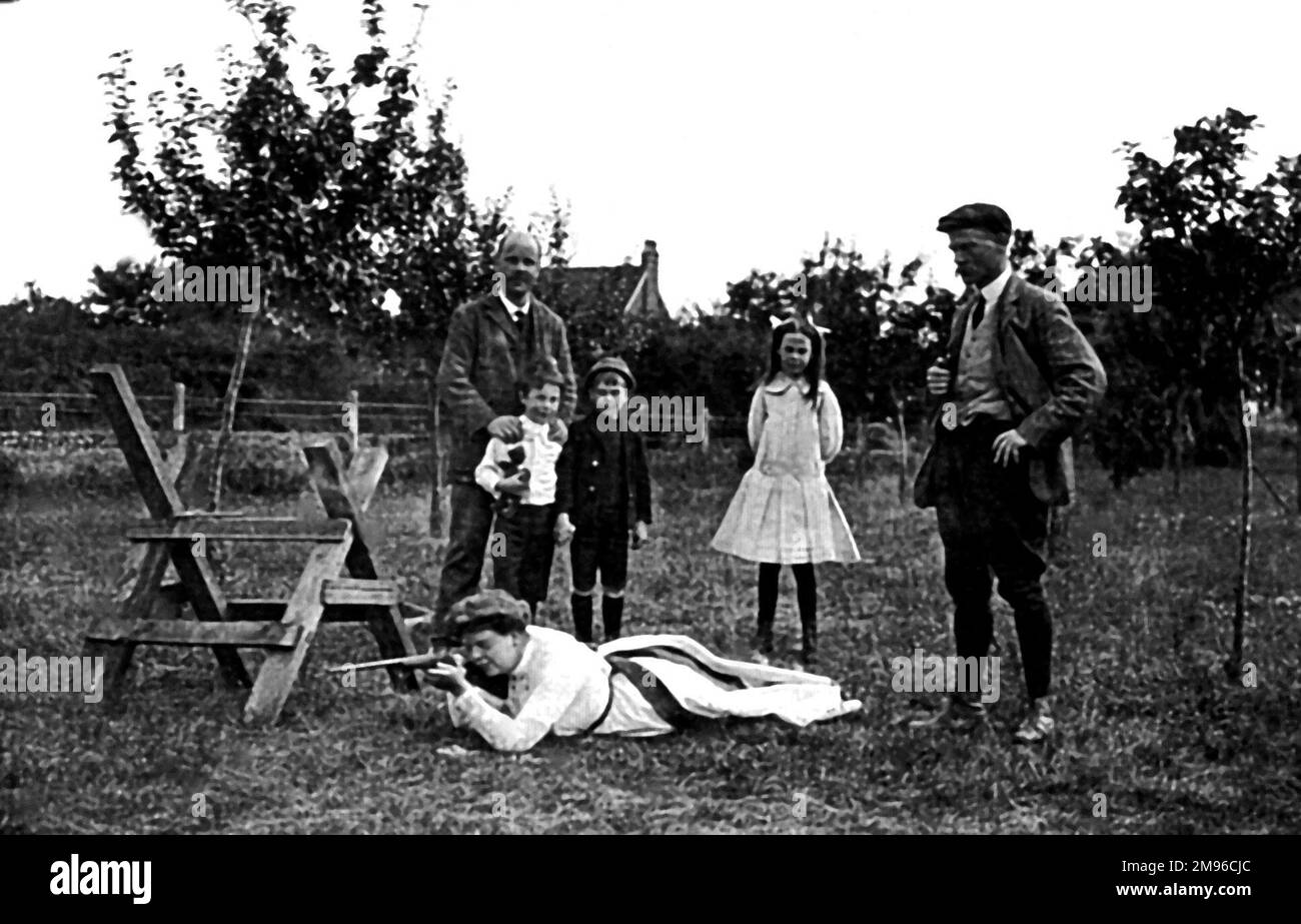 La famille Malby à votre guise dans leur jardin à Woodford, Essex. Reginald (1882-1924) observe (à droite) tandis qu'Eleanor (1886-1956) se trouve sur l'herbe, visant ce qui semble être un fusil. Banque D'Images